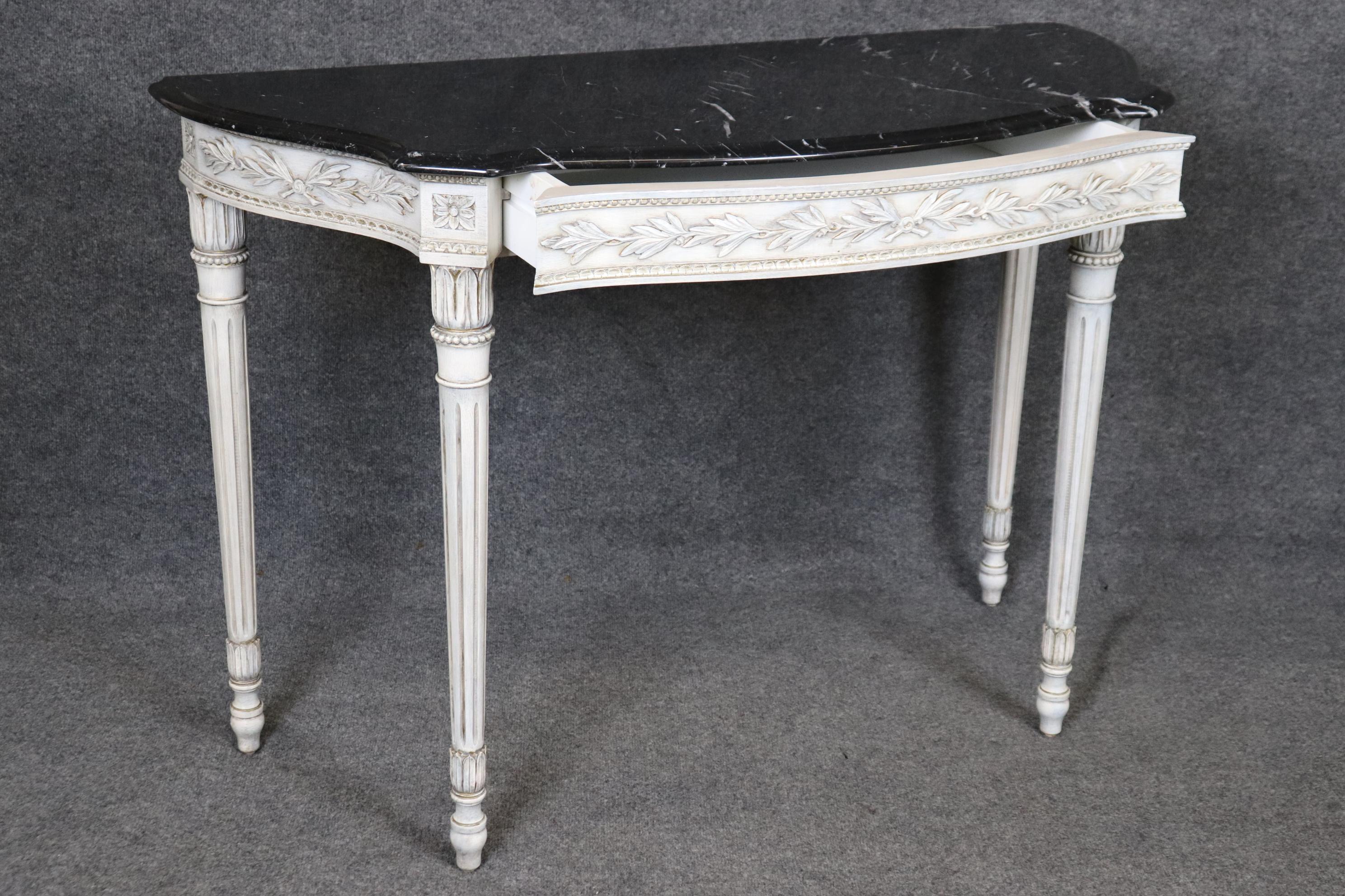 This is a rather rare pair of black and white veined marble top console tables with gorgeous hand-carved details in a white painted finish. The tables have hand-carved details reminiscent of Karges furniture but they are not marked. The finish as