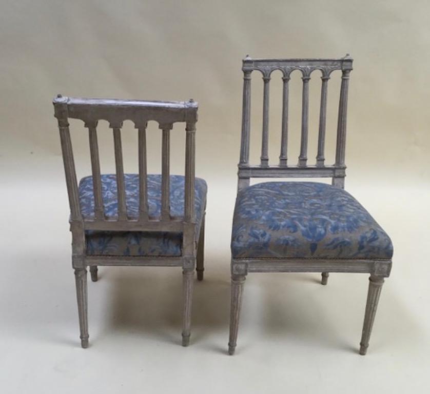 Two beautiful small side chairs upholstered in Fortuny fabric with fluted legs. Slightly different in sized and carved details.