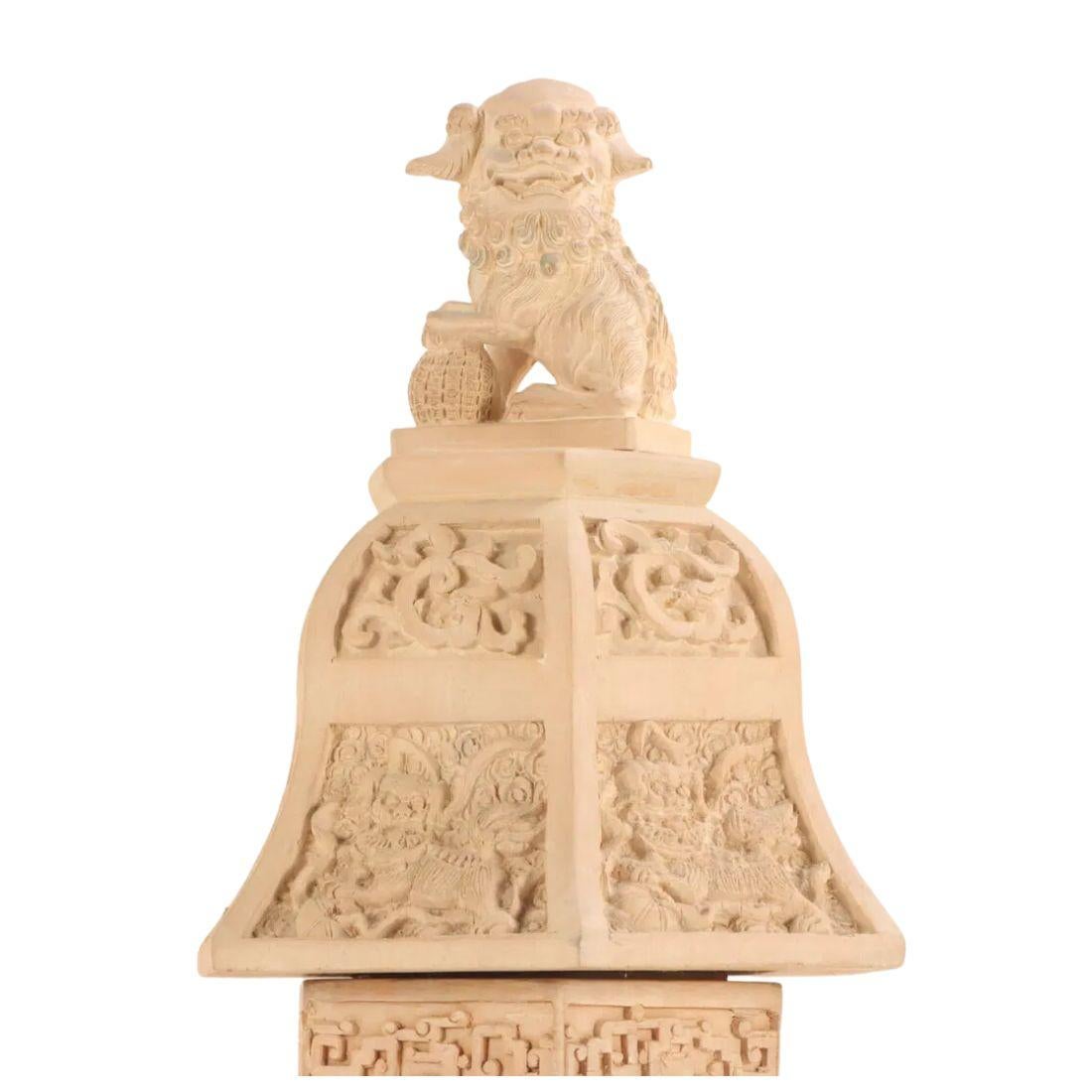 Une paire de grandes urnes asiatiques en bois sculptées et peintes de façon complexe, surmontées de chiens Foo, présentent une forme hexagonale distinctive, ajoutant une touche géométrique unique à leur design traditionnel. Le corps de chaque urne