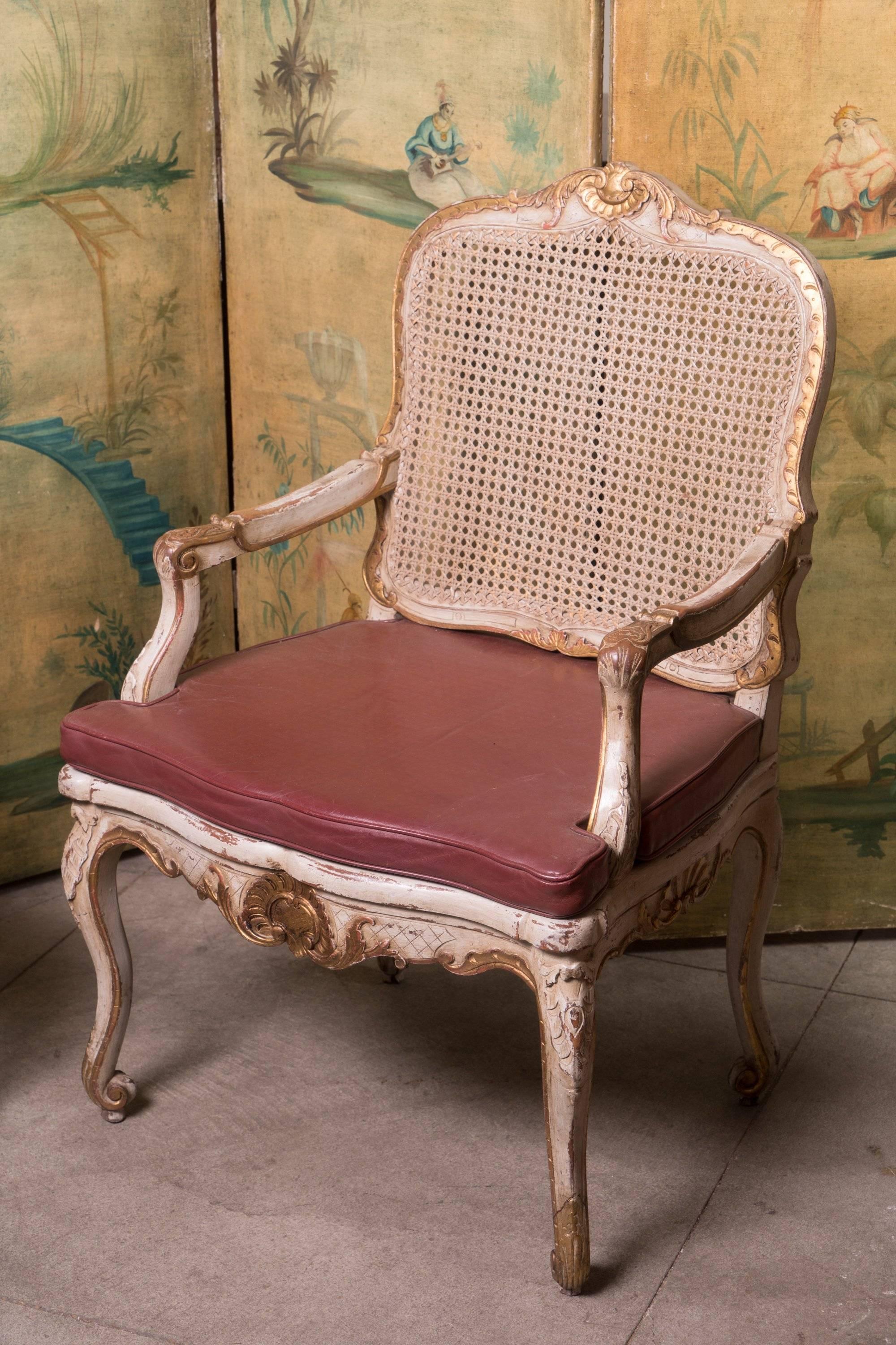 Pair of painted and gilded armchairs with leather seats.