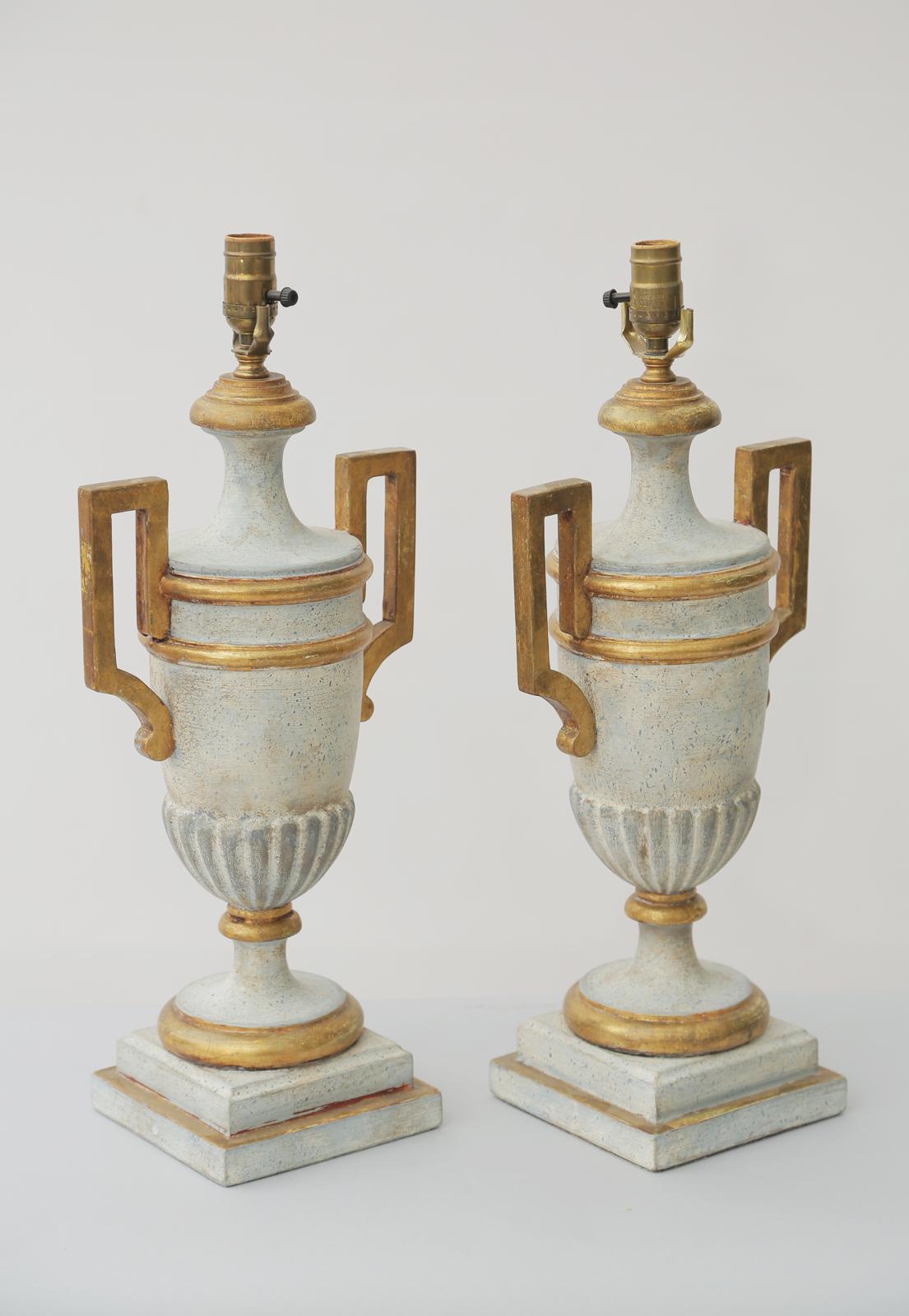 Pair of table lamps, of wood with a painted and parcel gilt finish showing natural wear; each lidded amphora urn-form body with exaggerated handles, semi-lobbed body, over socle base.

Stock ID: D3184