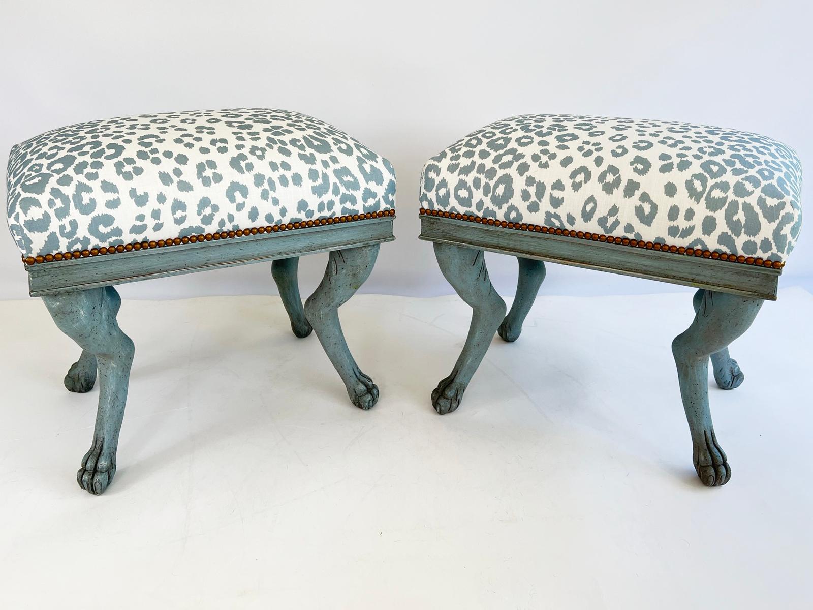 Pair of benches, having a painted finish showing natural wear. Each bench upholstered in a blue and white leopard print with nailheads, on a fielded frame. Four legs are carved into a hock-leg animal form, ending in paw feet.

Stock ID: D1635.