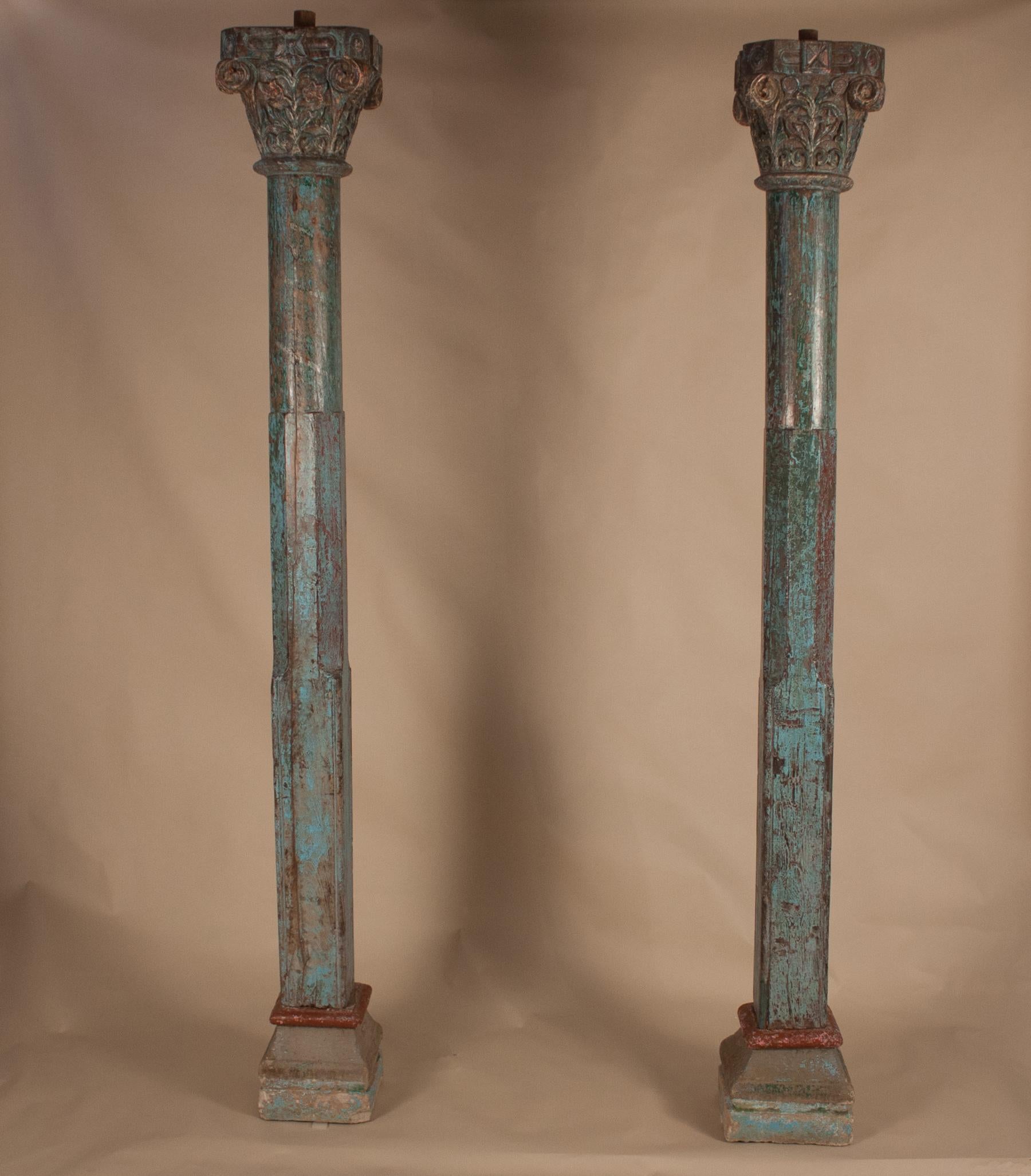 Beautiful pair of authentic teak wood columns from India, circa 1900. Colorful, yet subdued, the pillars have their original paint, a medley of blue and green, with hints of deep red. The Corinthian capitals are hand-carved with a floral design, and
