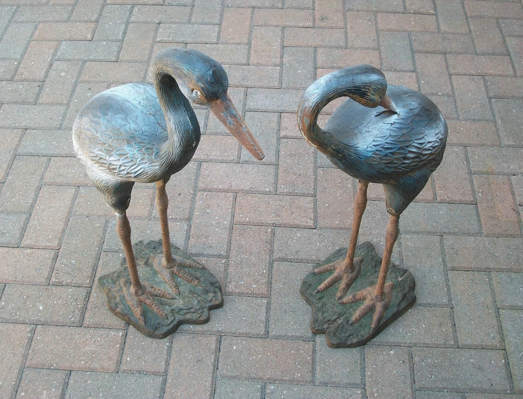 Vintage pair of cast iron 'Heron' garden sculptures - suitable for indoor/outdoor use - featuring a great aged patina with remnants of a polychrome painted finish in areas - articulated details to the body, wings, legs and base - each bird cast in