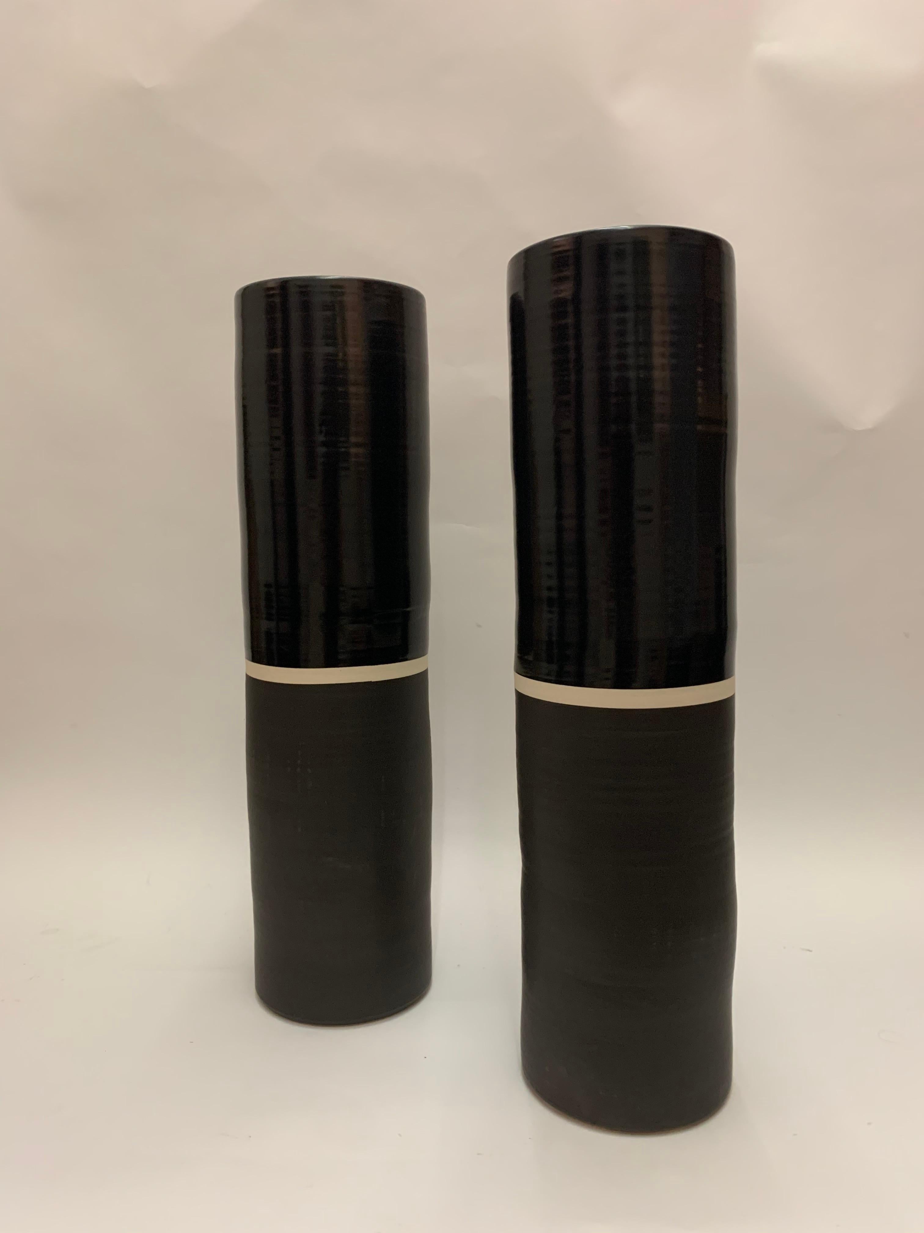 Pair of Minimalist ceramic vases by esteemed designer Calvin Klein from his eponymous home collection. Using two different style paint techniques the vases have a lacquer top and matte base with a white band creating space in the middle.

Property