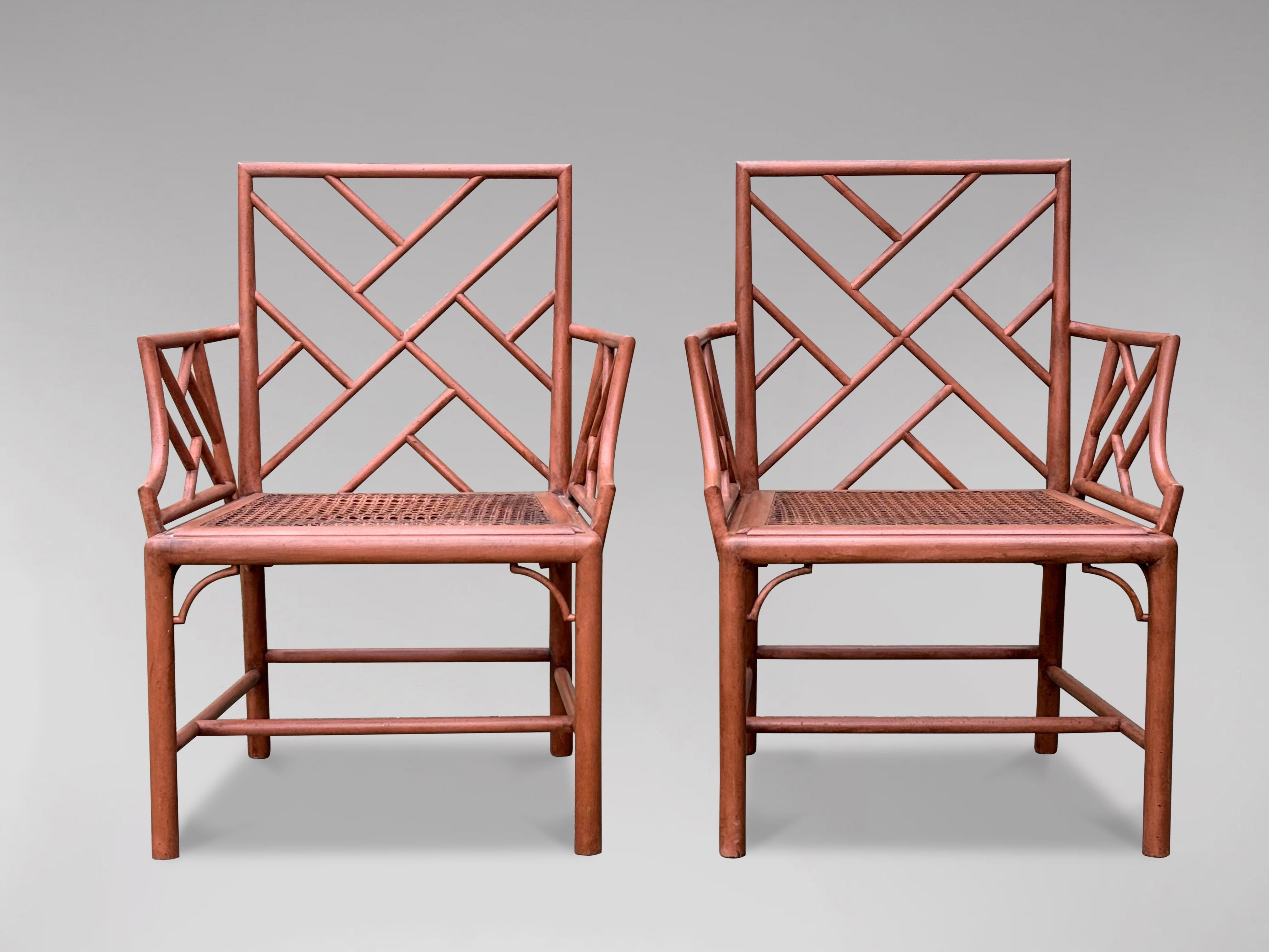 A pair of superb mid century Chippendale style faux bamboo armchairs in a wonderful patinated sanguine colour. The chairs are in overall good condition and include a separate blue velvet seat cushion over the caned seats. The frames have a carved