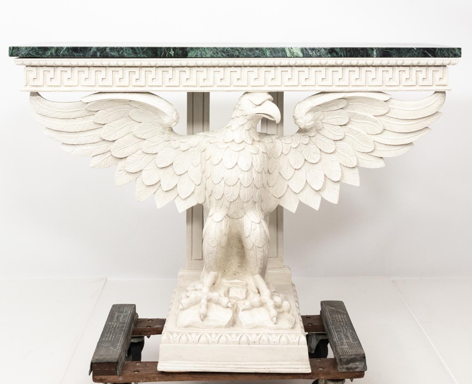 Pair of white painted Federal Revival style marble-top consoles with carved eagle bases and Greek key trim on the skirt, circa 20th century.
 