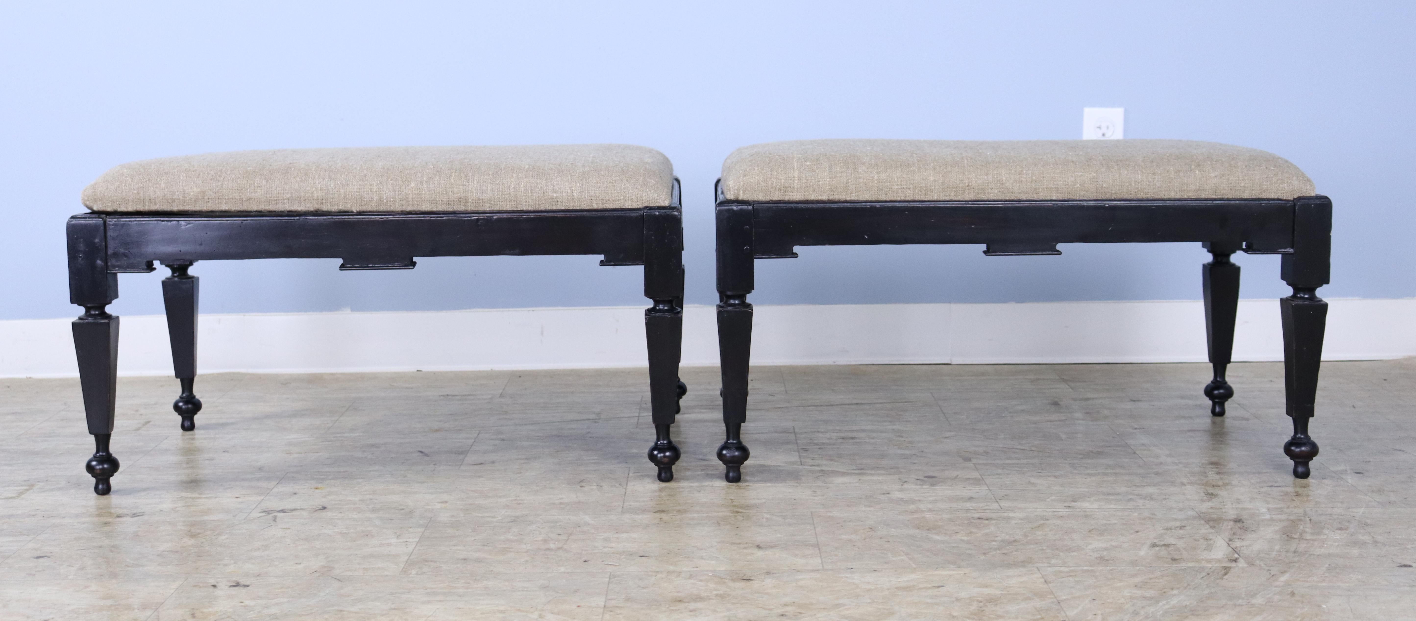 A pair of 18th Century or early 19th Century Italian stools, recently painted black and slightly distressed.  The removable seats have been upholstered in a slightly fuzzy light brown woven material.  