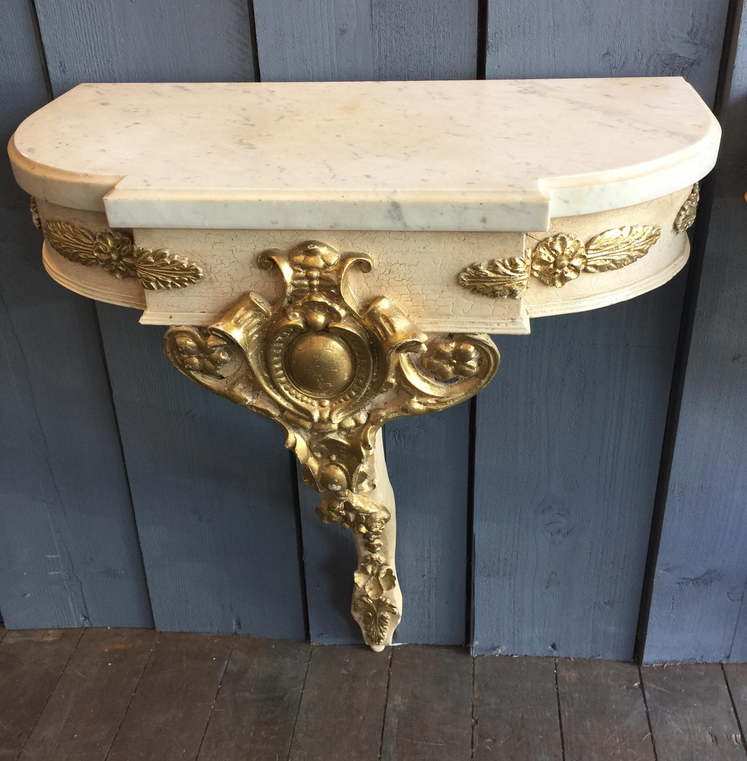 A lovely pair of painted Empire style console tables or nightstands. Cream painted with gilt decoration in a slightly distressed finish. Nicely designed with a good color. Marble is in good condition. Probably made mid to the third quarter of the