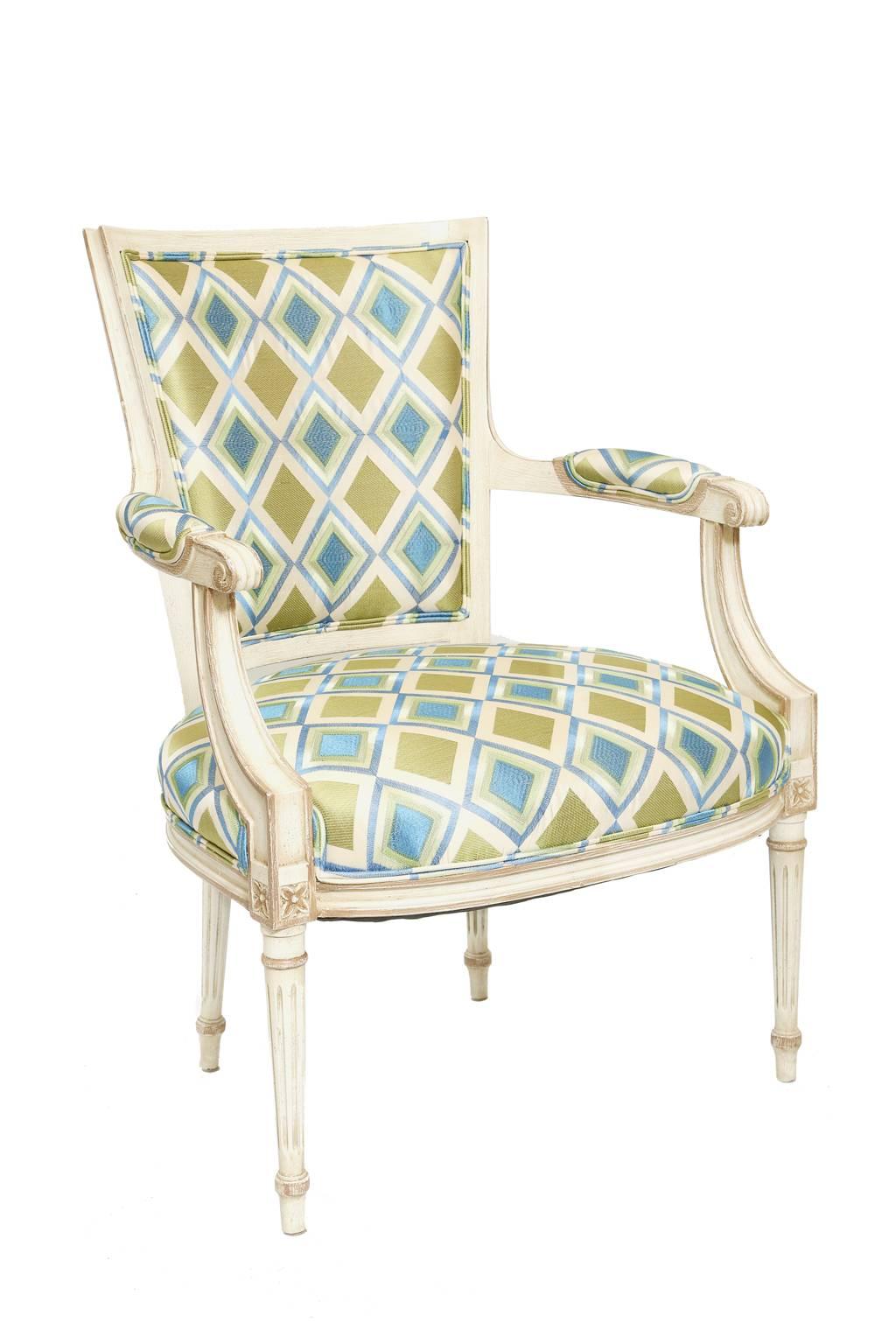 Pair of armchairs, each having a molded frame, with painted finish, showing natural wear; each tapering, shield-form, padded back, to crown seat, outswept arms with elbow rests, ending in scrolls, supported by saber terminals, bowed apron raised on