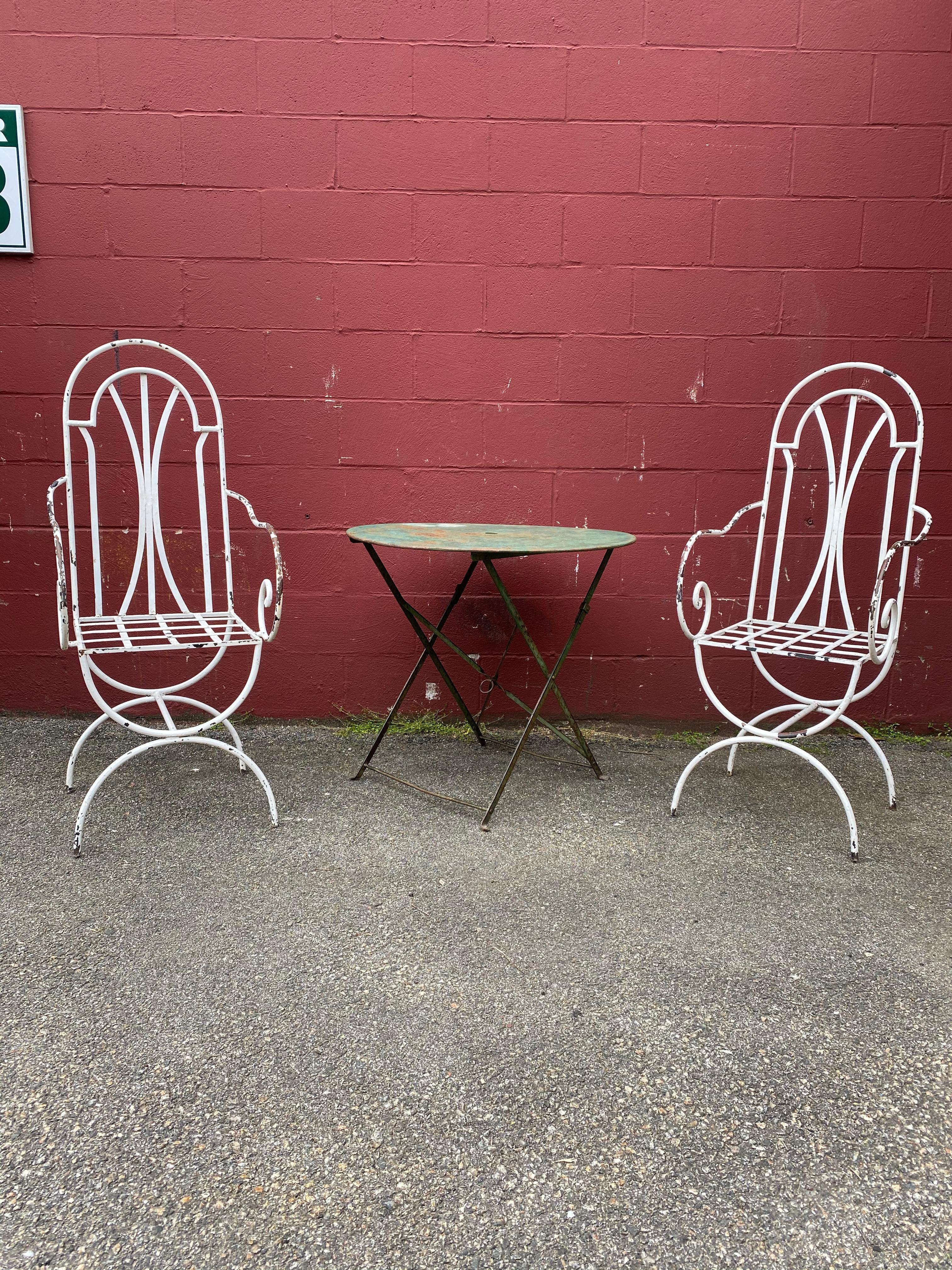 This pair of vintage French garden chairs is a timeless and elegant addition to any outdoor space. The tall back design offers ample support for comfortable seating, while the white painted iron construction is both durable and sturdy. The paint is