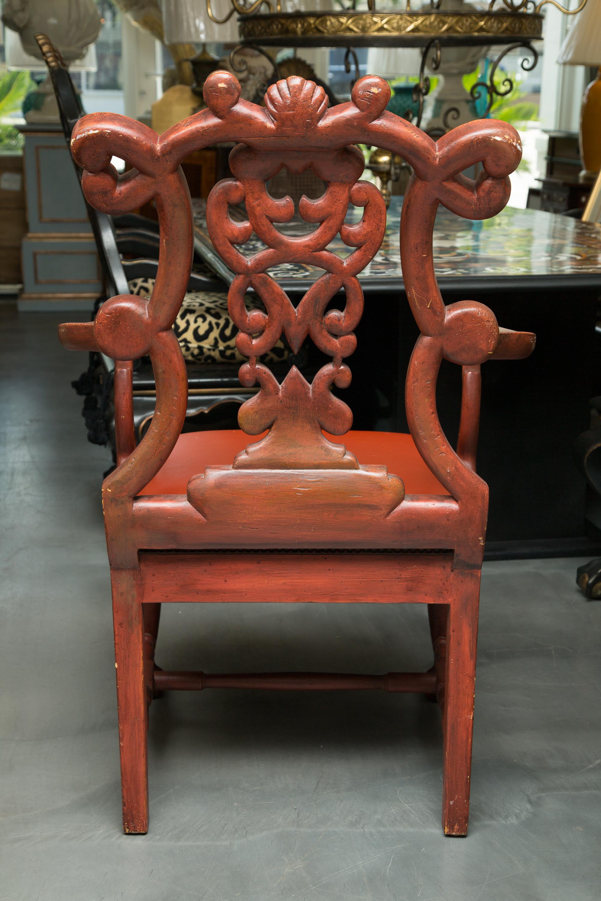 This is a stately pair of Italian armchairs with chinoiserie painted overall on a parcel-gilt and Chinese-red ground. The undulating top rail is over a backsplash of interlocking scrolls. There is an upholstered leather seat stabilized by brass