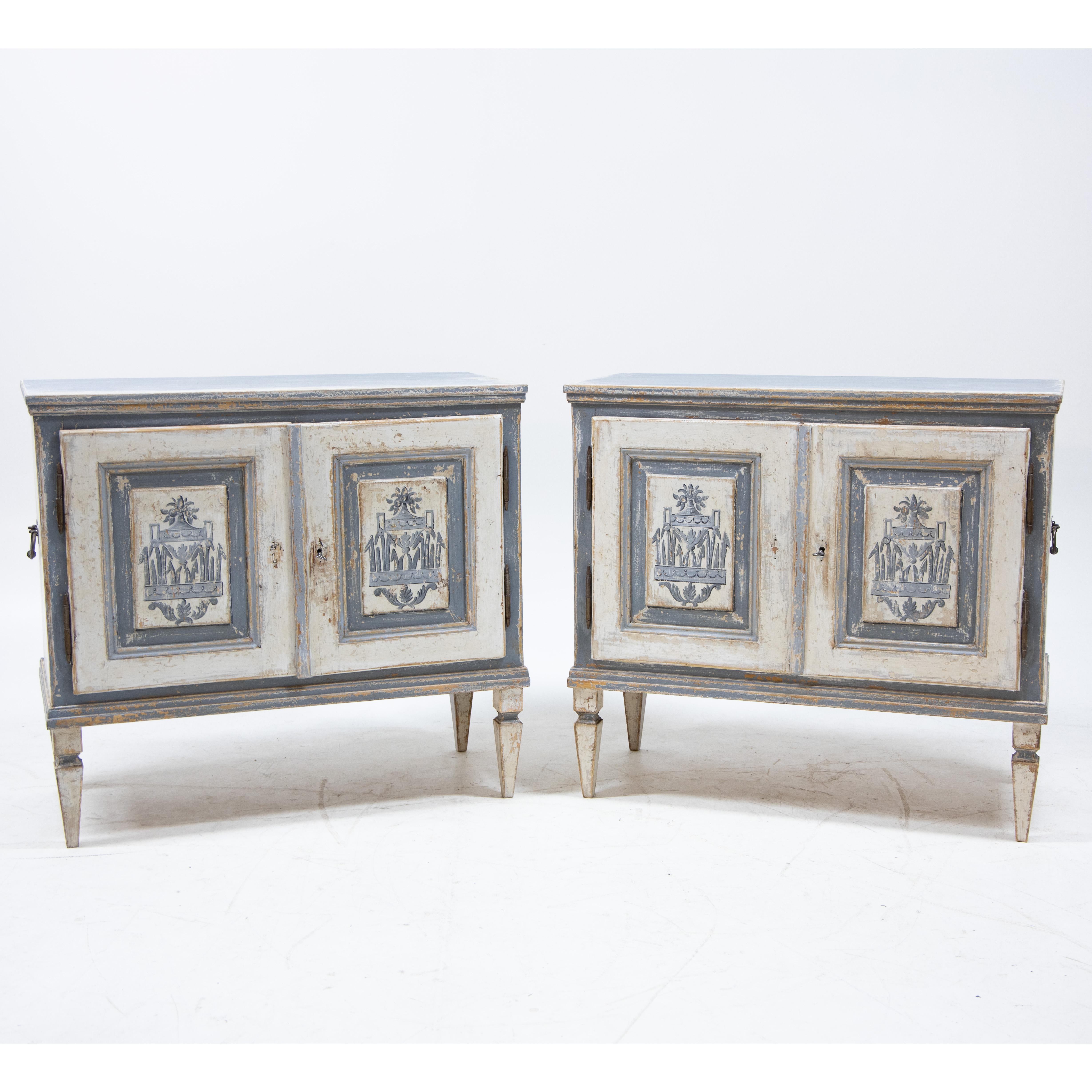 Pair of two-door sideboards on square pointed feet with coffered doors and iron side handles. The setting in blue and grey is new and has been decoratively rubbed through. The fronts of the doors are painted with urn motifs based on historical