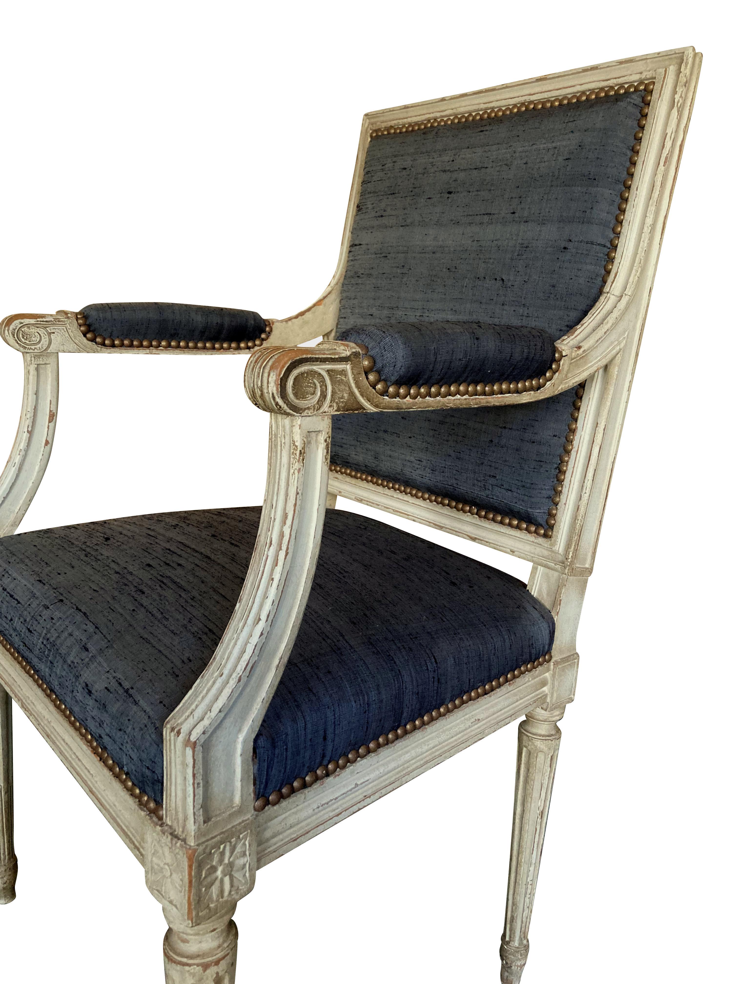 A pair of French Louis XVI style carved and painted armchairs, with the original paints and newly upoholstered in charcoal textured silk.