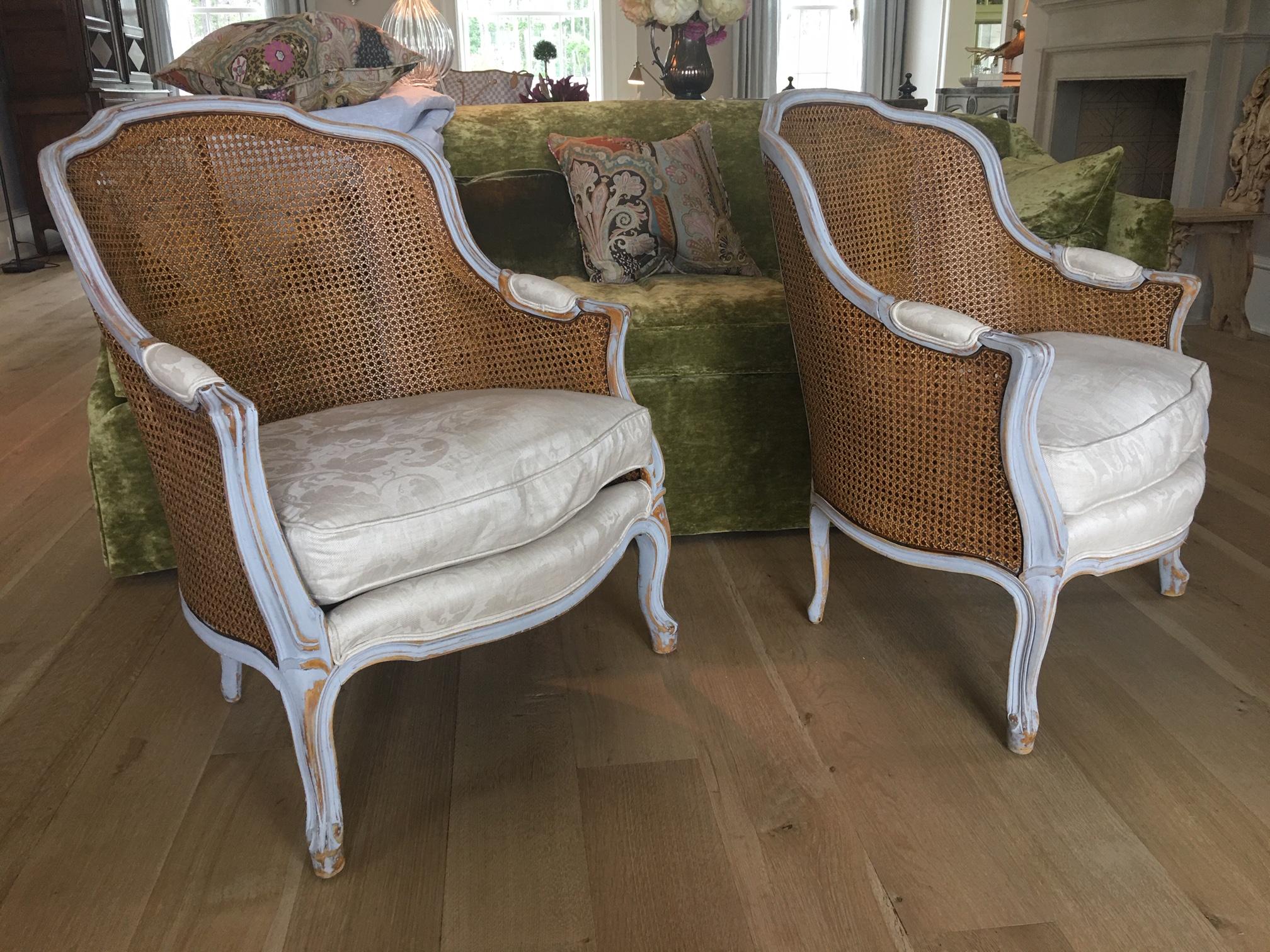 Pair of painted Louis XVI style cane back side chairs, early 20th century.  Side panels are double caned, center back panel is single caned.  Upholstered in cowtan and tout linen. Measures: 30