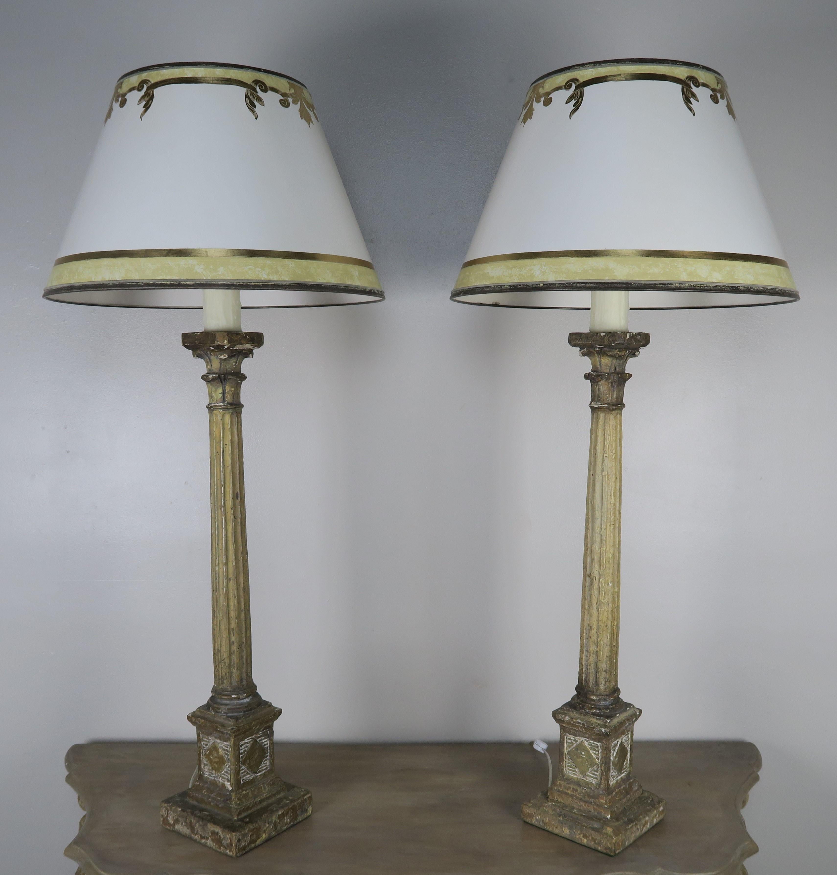 Pair of painted neoclassical style fluted column lamps with capitals crowned with hand painted parchment shades. The lamps are newly rewired and ready to use.