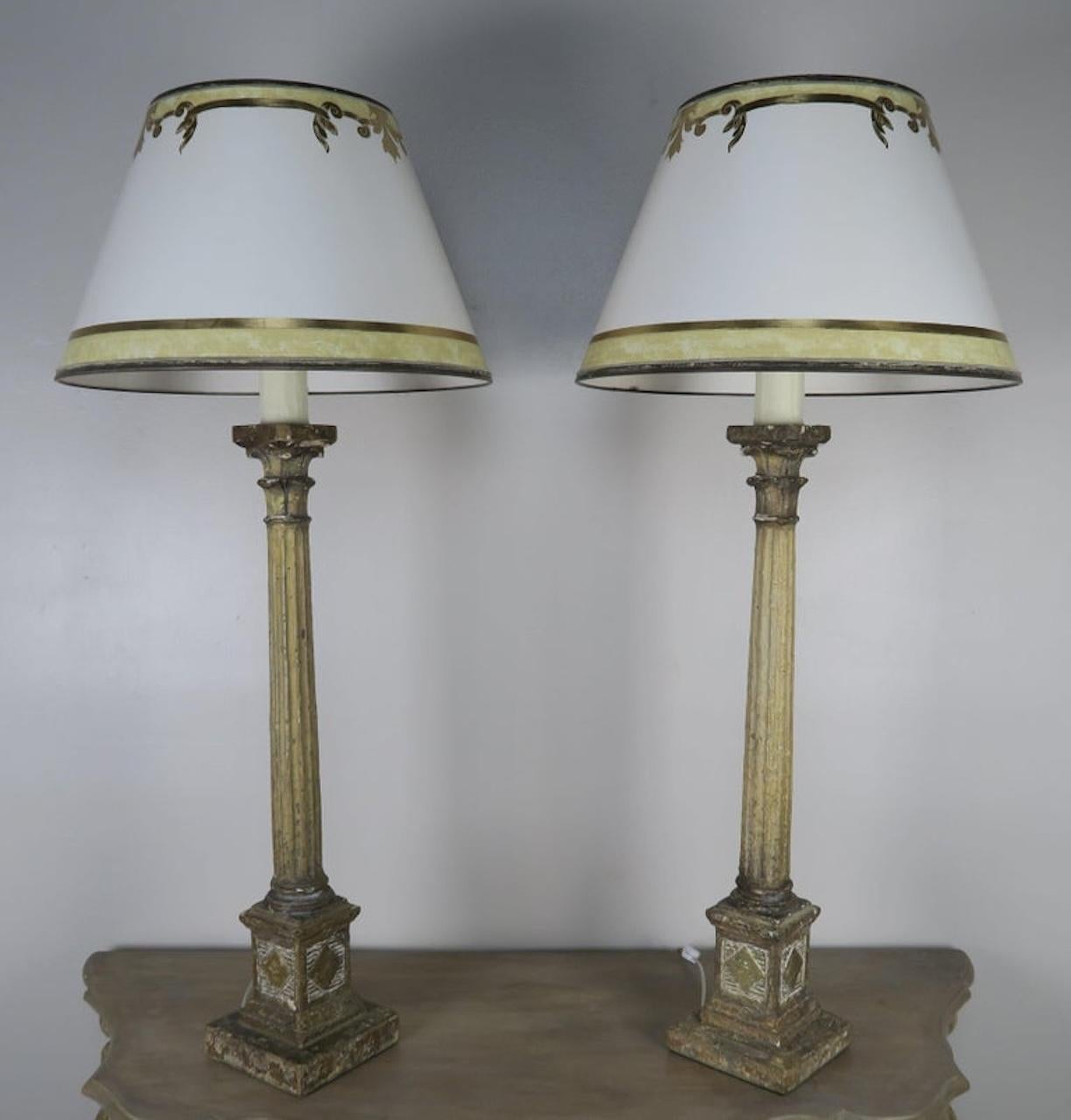Pareja de lámparas de columnas estriadas de estilo neoclásico pintadas con capiteles coronados con pantallas de pergamino pintadas a mano. Las lámparas están recién recableadas y listas para usar.
