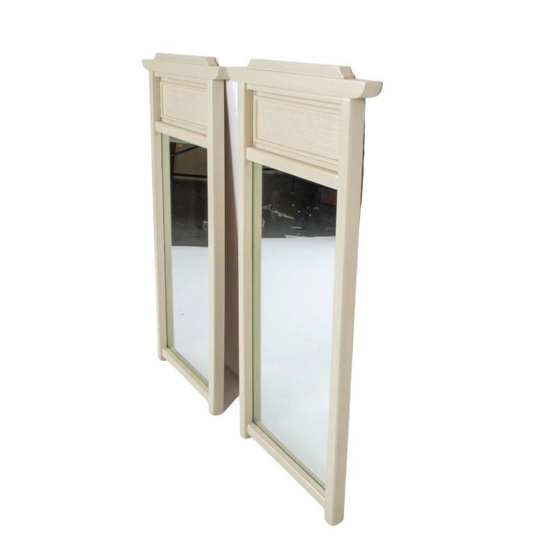 A pair of painted pagoda top mirrors with an inset panel at top of woven wicker.  The entire frame is painted off-white.  A contemporary Asian motif pair of mirrors in a neutral shade of cream.
