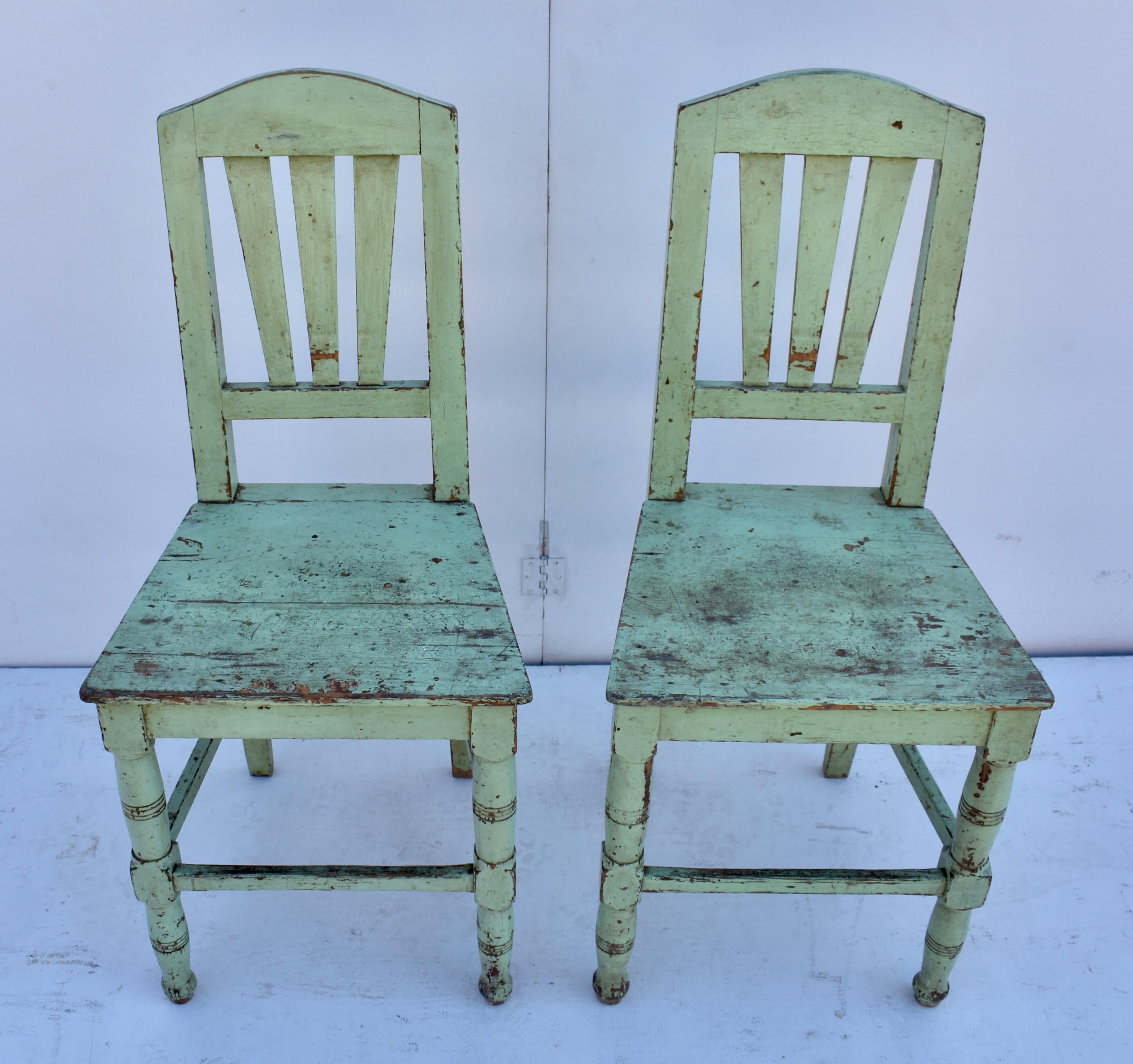 This is an attractive pair of painted pine plank seat chairs. The arched top rail encloses three broad splats. The two back legs are straight and those at the front are turned, with stretchers at the front and sides. The flat plank seat may look