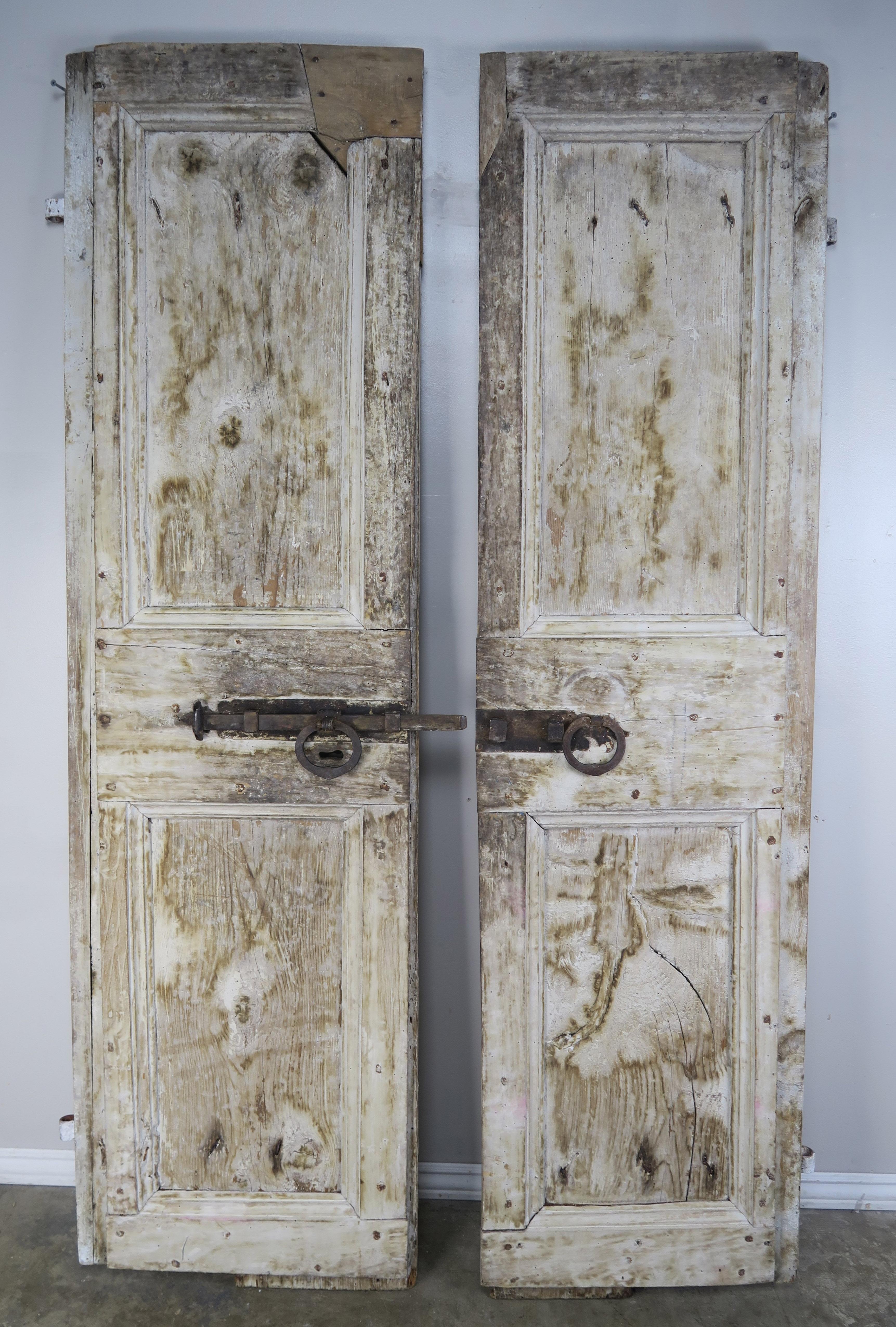 Pair of rustic Swedish distressed white painted doors with original heavy wrought iron hardware. Beautiful distressed finish with wood exposed underneath.