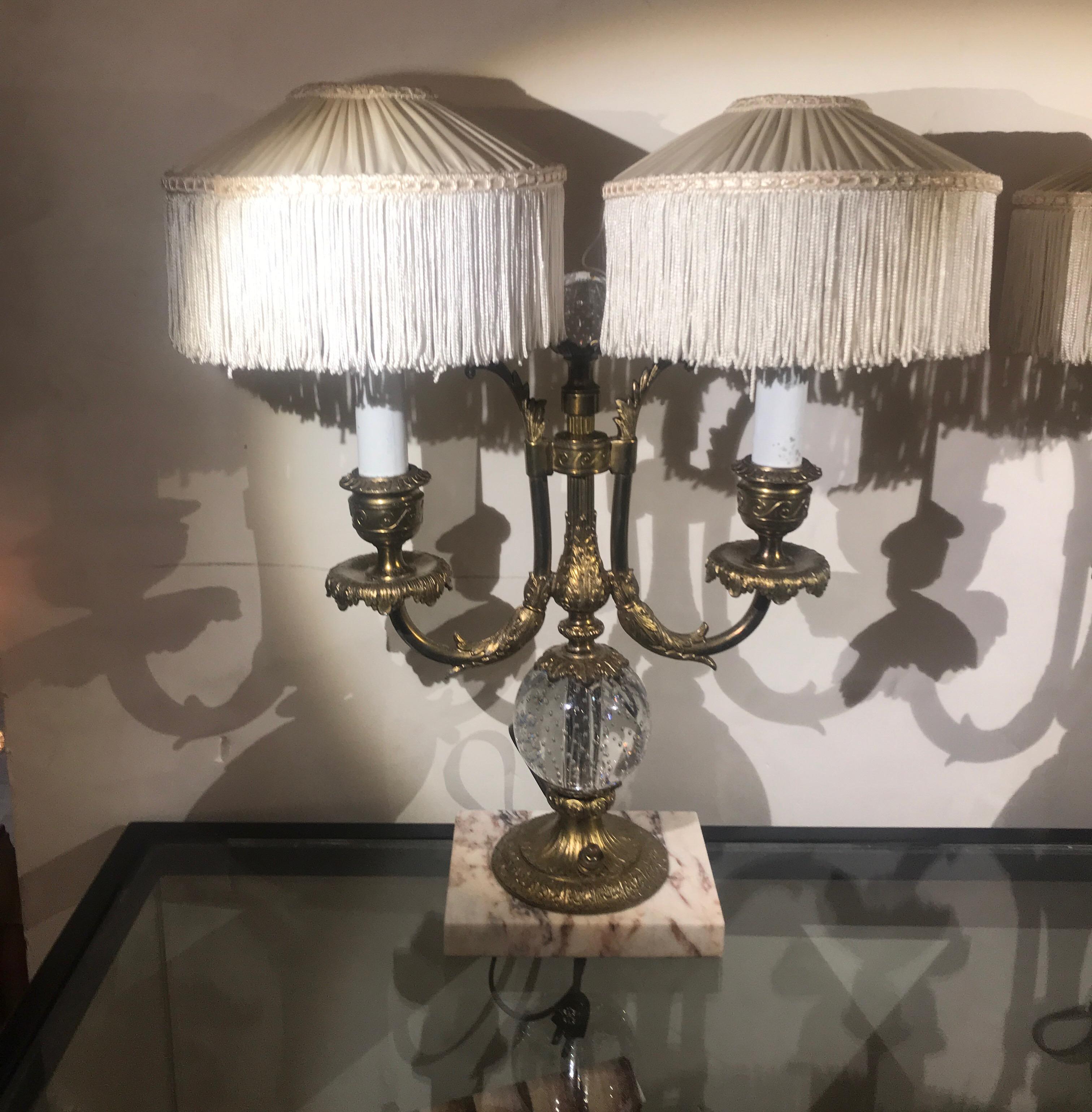 A pair of two light candelabra lamps with fringed hand pleated custom silk shades by Pairpoint. The original gilt finish with Classic glass spheres, one smaller at the top and the second larger at the base. These are highly decorative lamps perfect