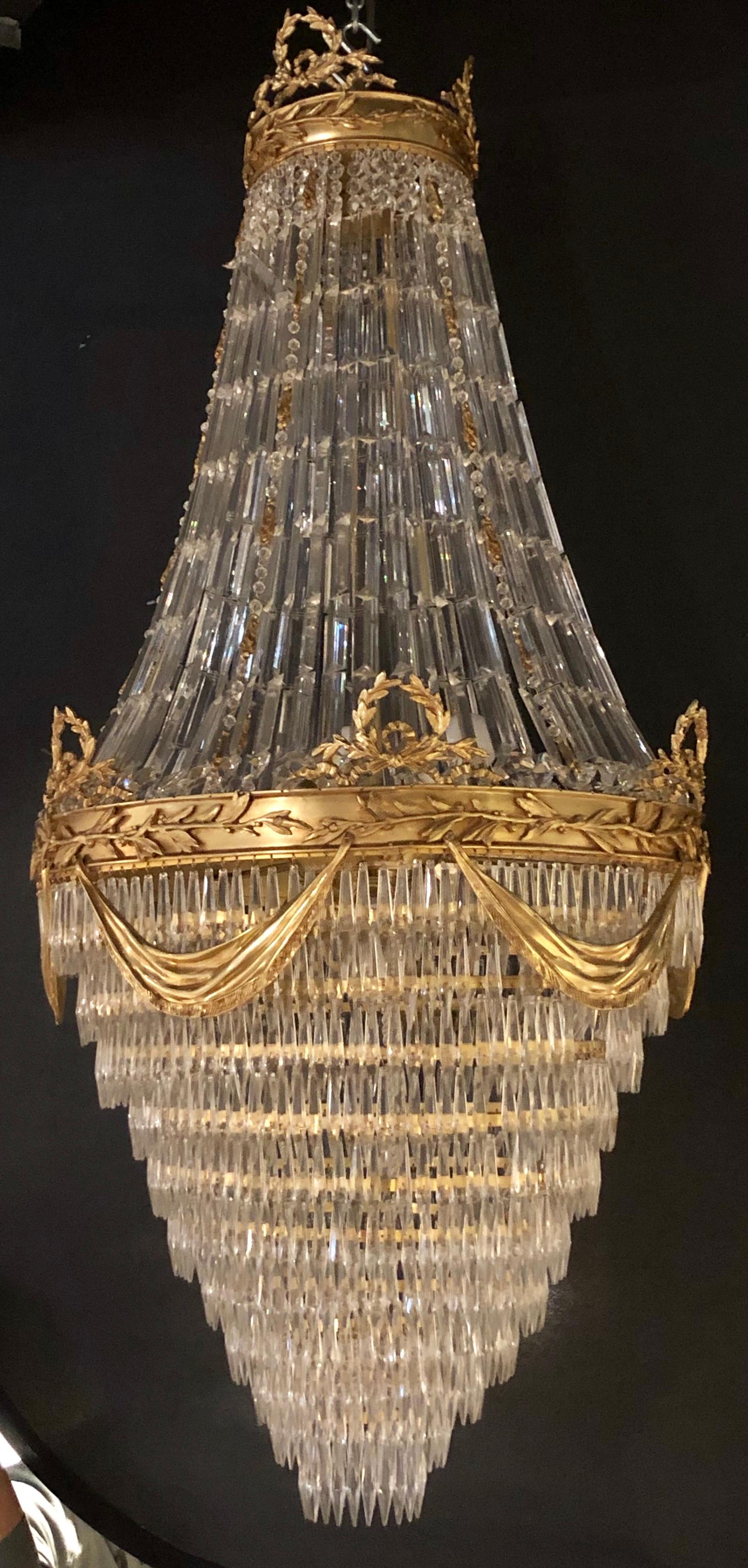 Pair of spectacular Palatial Crystal Swag design Louis XVI style chandeliers in bronze having a floral and swag with drapery form design. These large and impressive chandeliers have been recently rewired and are ready to hang in any palace befitting