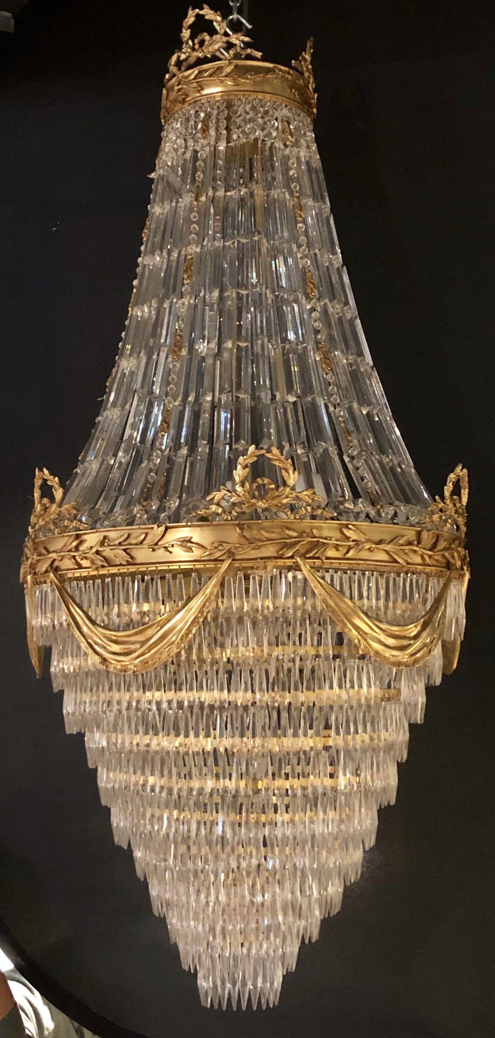 Pair of spectacular palatial crystal swag design Louis XVI style chandeliers in bronze having a floral and swag with drapery form design. These large and impressive chandeliers have been recently rewired and are ready to hang in any palace befitting