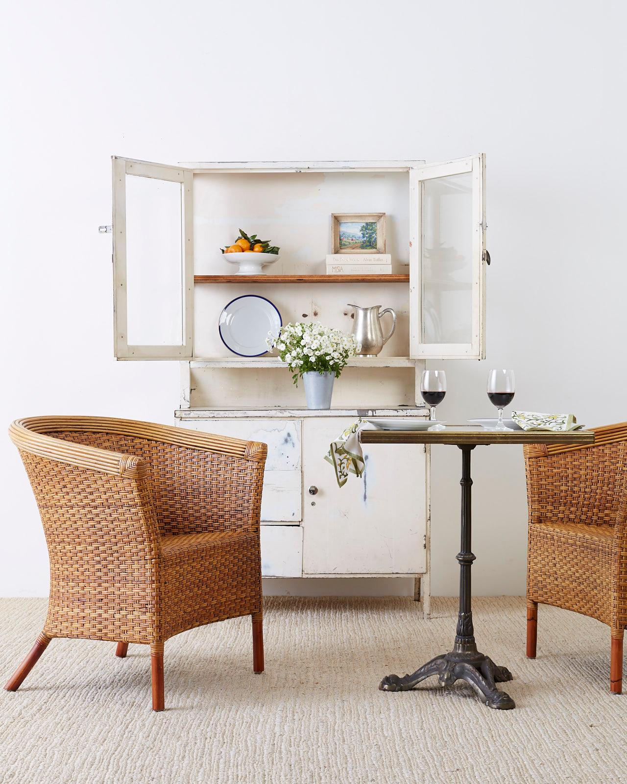 Stylish pair of bamboo rattan and wicker organic modern barrel back chairs made by Palecek. Featuring a bamboo rattan frame covered in woven wicker fiber. Natural rattan crest rail gives the chair a sleek look. The chairs have an hour glass profile