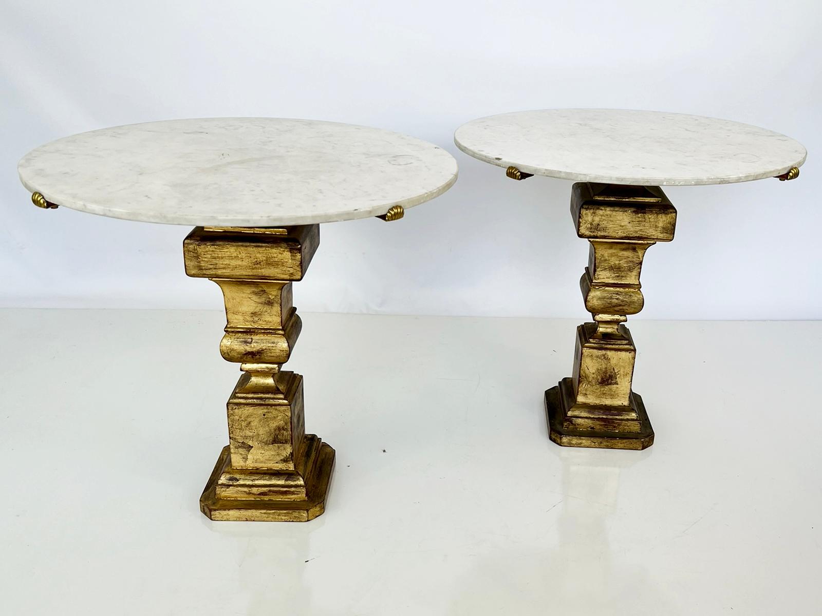 Pair of side tables, by the Italian design house, Palladio. Each table having a round top of Carrara marble, held by scallop shell clips, of brass. The pedestal bases of gilt metal with a square-section, balustrade shape, on base with canted