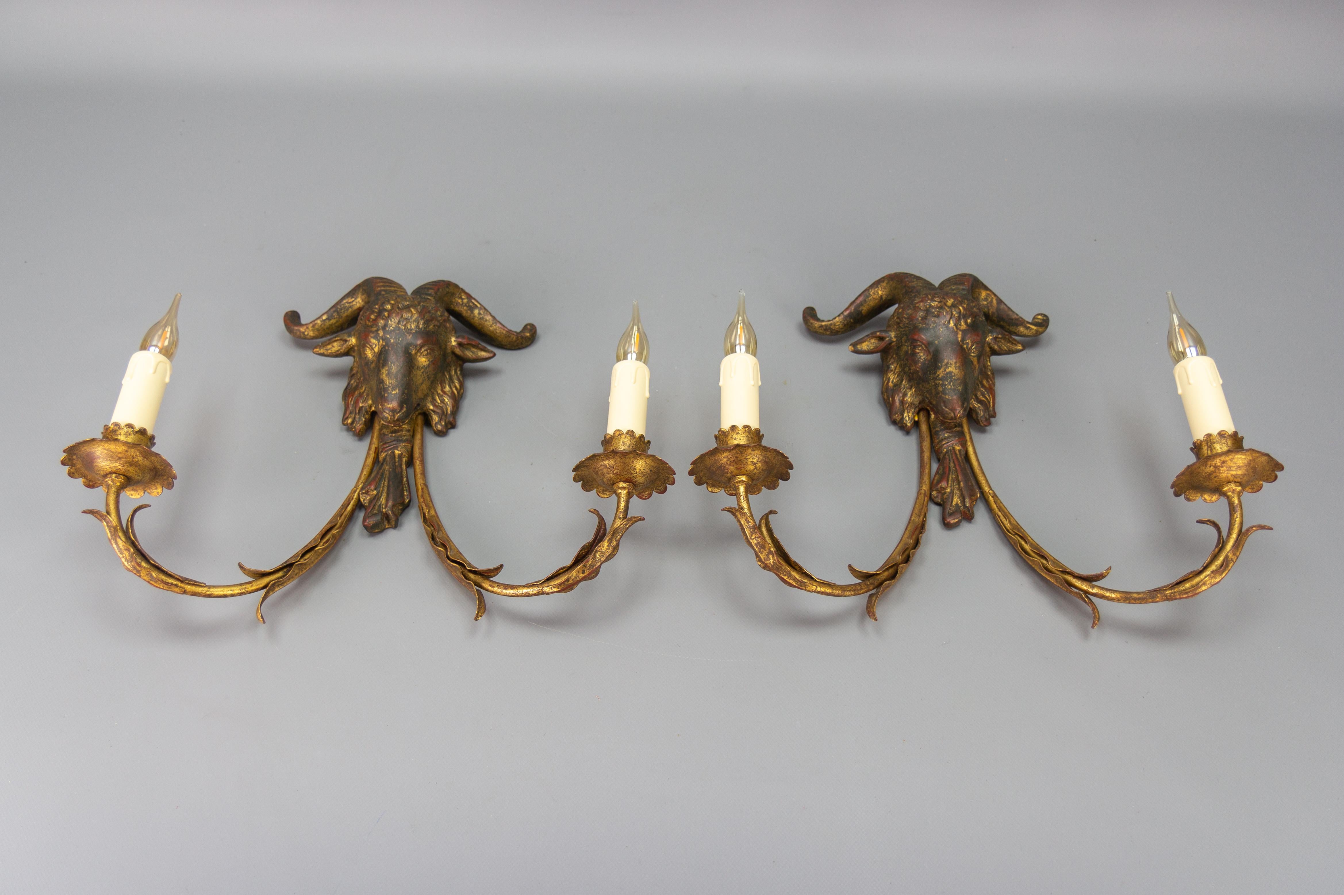Pair of Palladio gilt metal and giltwood ram's head two-light sconces from circa the 1960s.
This stunning pair of Italian wall lamps each features two gold-plated metal arms with leaf decoration and a golden-patinated wooden ram's head at the center