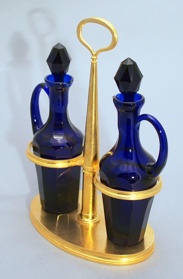 Pair of Italian hand hammered sterling silver gold washed cruet sets in the style of Greek jeweler Lalaounis. The cruet sets consist of two cobalt blue bottles with stoppers, the body with softly hammered finish, having notched handles. The maker is