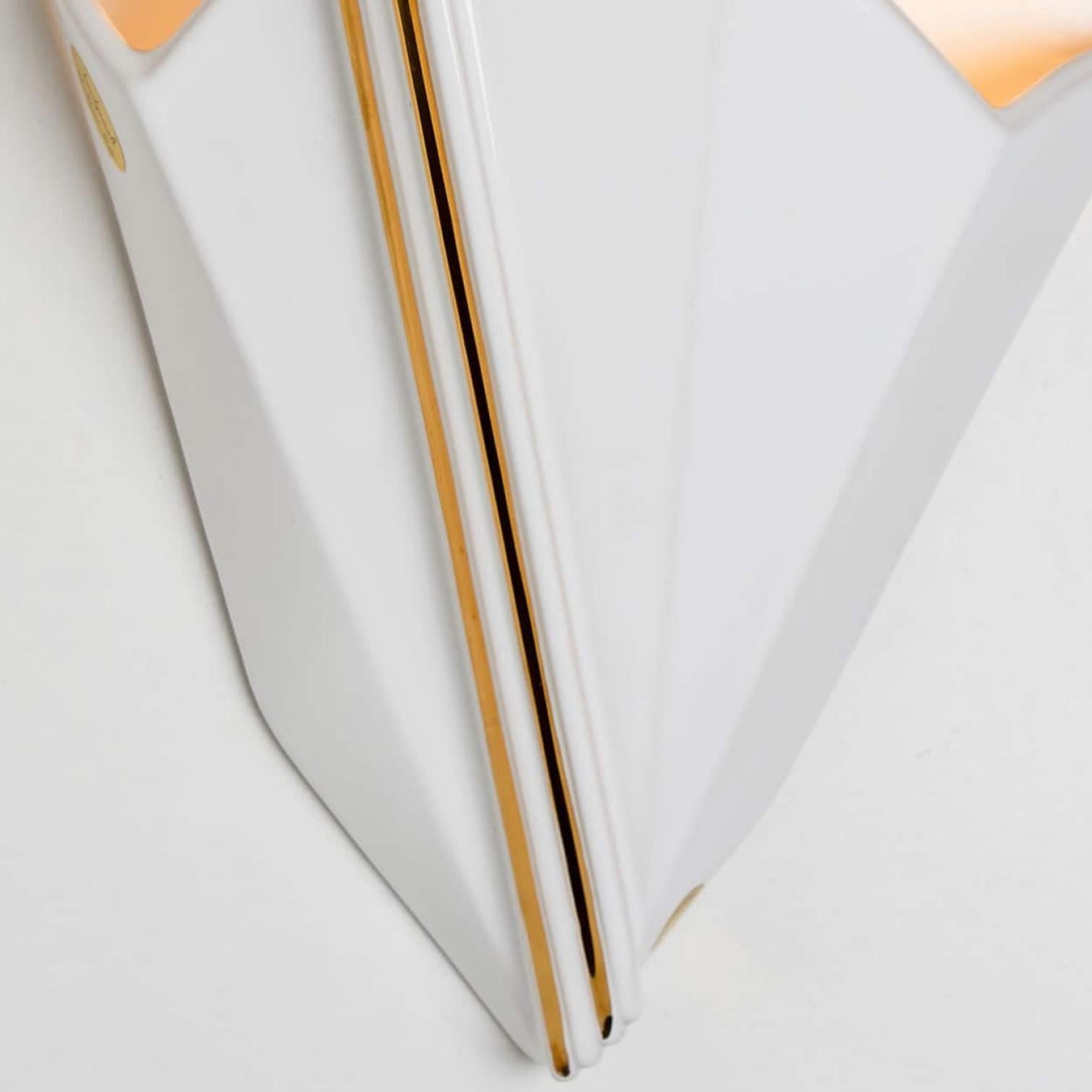 Precioso aplique de porcelana, de cerámica rayada blanca y dorada, fabricado en los años 70 en Alemania.

Diseño gráfico y elegante.

Nosotros hemos utilizado bombillas transparentes (ver imágenes), pero las bombillas de espejo plateadas o doradas,