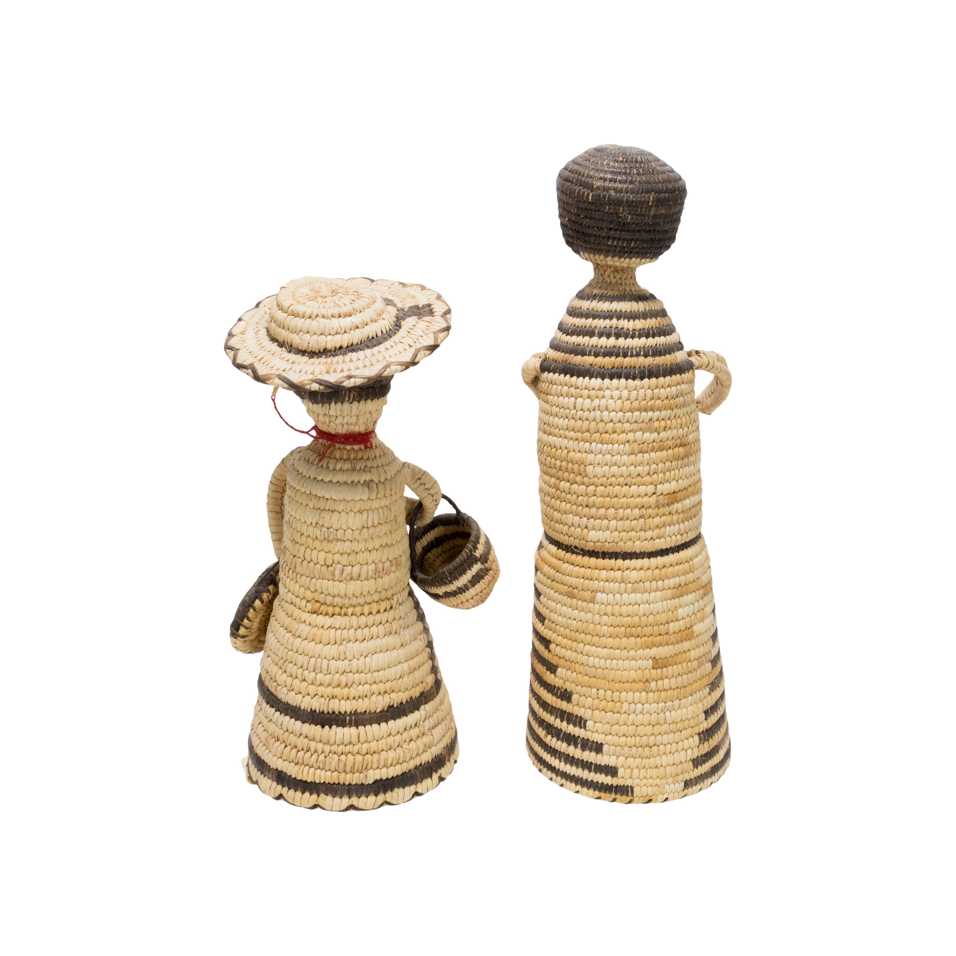 Pair of Papago basketry dolls. Male and female, both with hats (one not photographed). With original sales tag “Arizona. Made by Sally Lopez at Santa Rosa Valley.” Ex. Dunning. Papago baskets are handcrafted of beargrass, yucca cactus (white or
