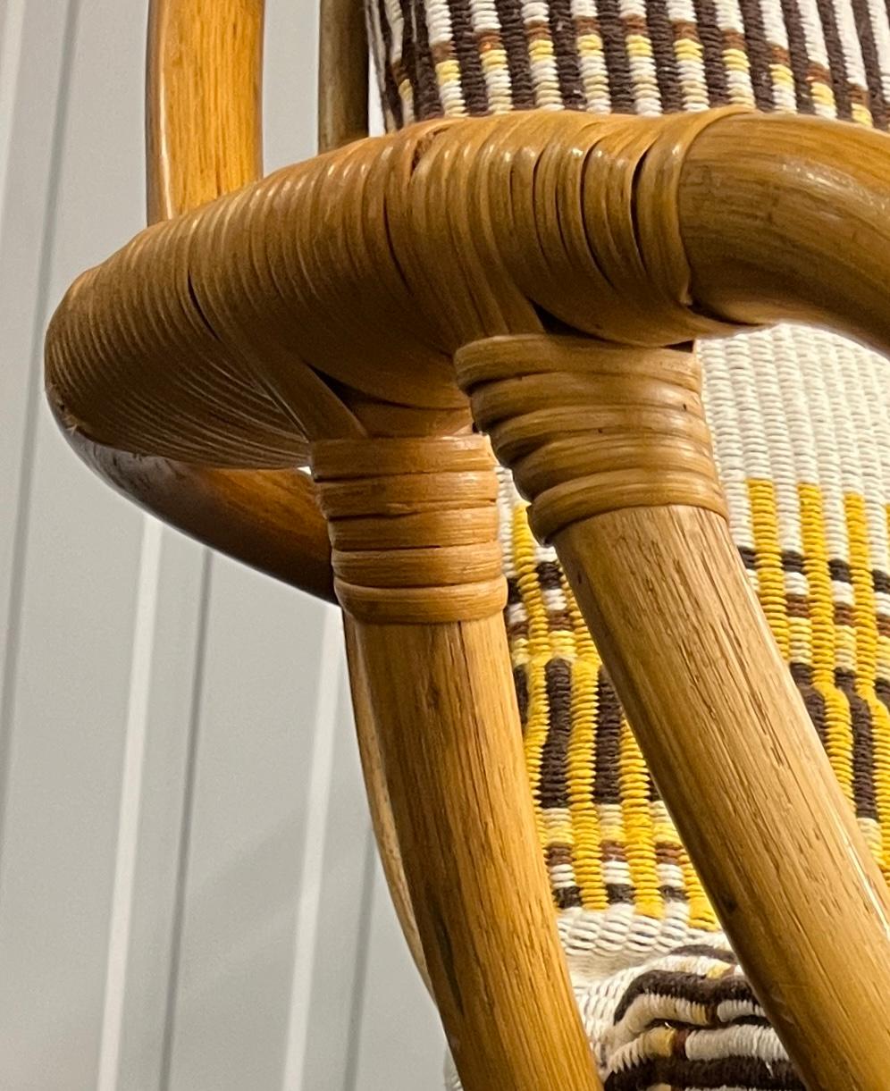 A pair of vintage rattan swivel chairs with a beautifully handcrafted frame, featuring a solid yet lightweight design. The base is composed of concentric rattan rings, allowing rotation. The high backrest and curved armrests provide both support and