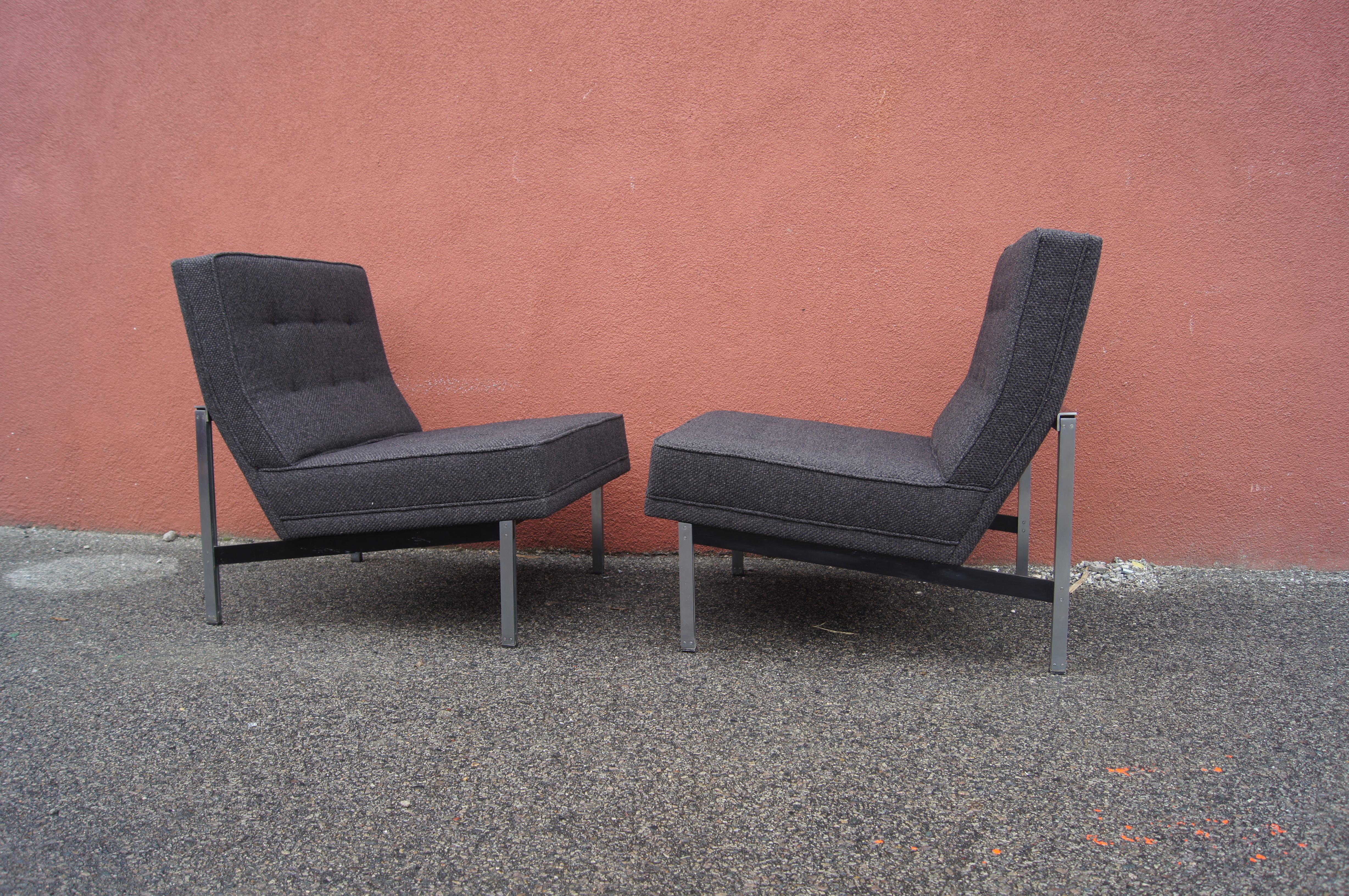 Florence Knoll's parallel bar lounge chair, model 51, places an armless angled seat upon a squared-off steel frame with a brushed chrome and black finish. The tufted back and seat of this pair have been newly reupholstered in Knoll's Ferry bouclé in
