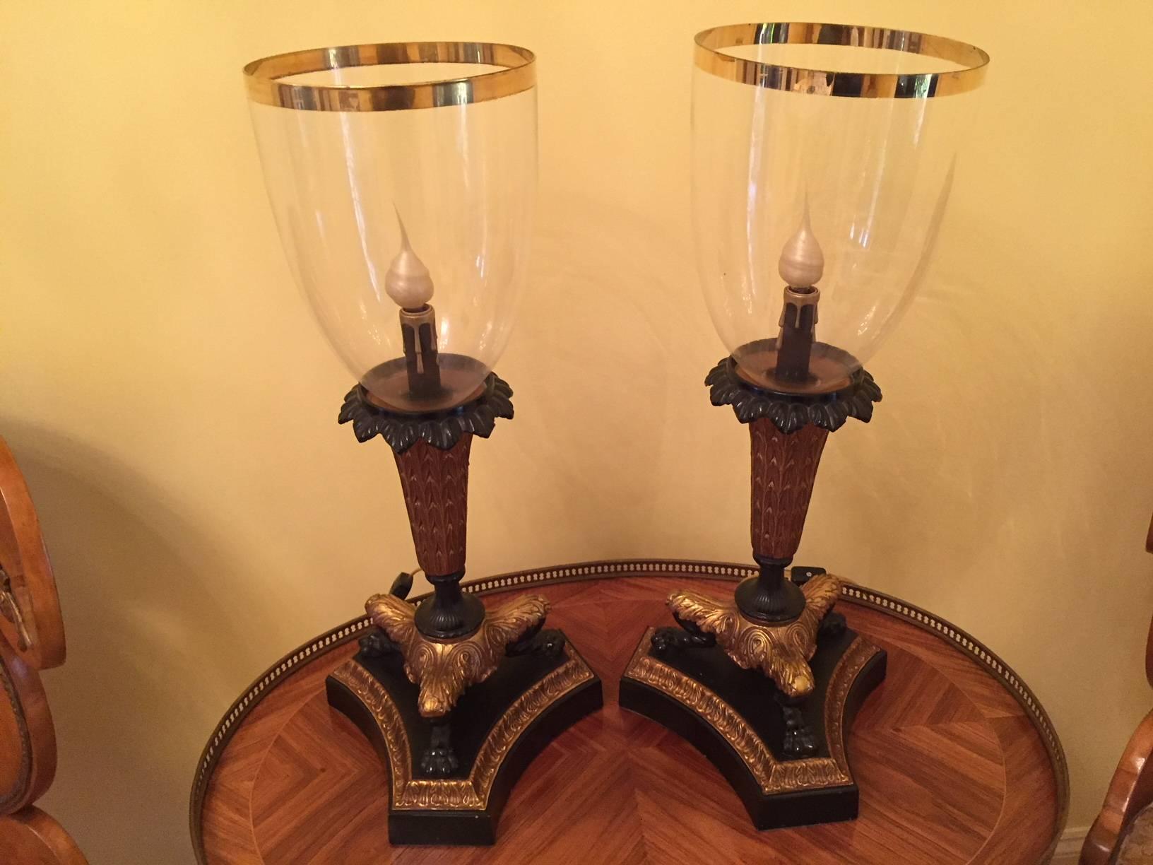 Charles X style candlestick lamps with gilt trim glass shades fitted into the patinated and gilt bronze bases.