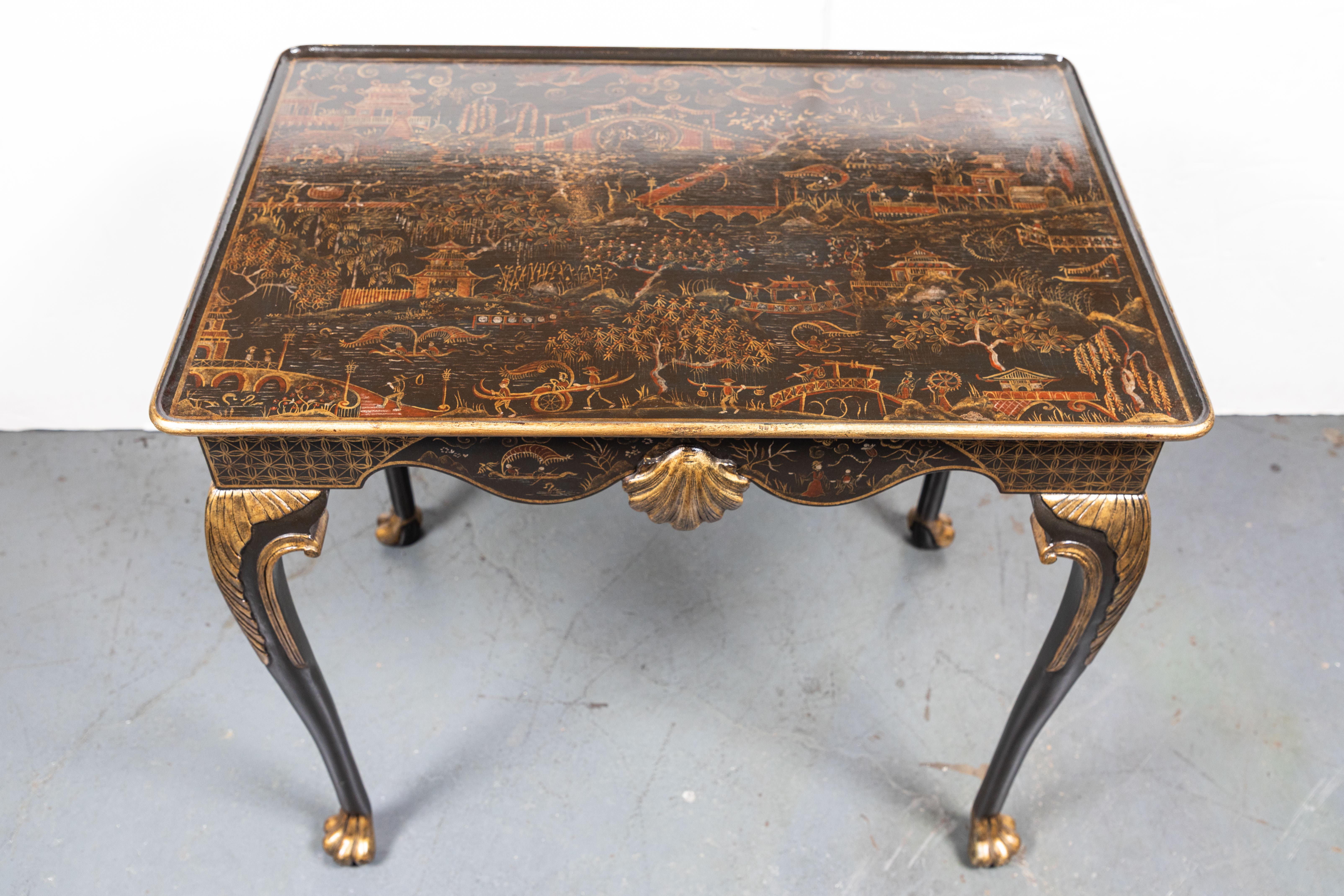 Fabulous pair of midcentury, hand painted, ebonized, parcel-gilt, Chinoiserie side tables with scrolling aprons punctuated by a relief-carved shell. Each terminating on paw feet.