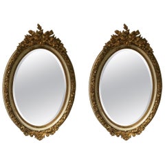 Pair of Parcel Paint and Parcel Gilt Beveled Oval Mirrors, with Bird Carvings