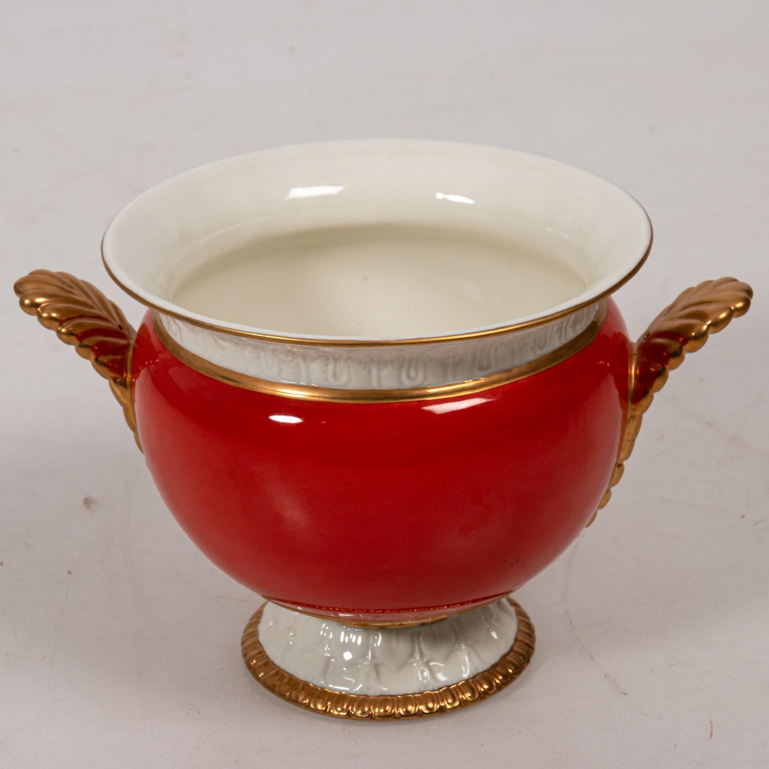 Paris Royal porcelain cache pots in burnt orange with gilt handles and trim, circa 1950s. The piece also features a cream painted interior. Please note of wear consistent with age including minor discoloration to the interior. Made in France.