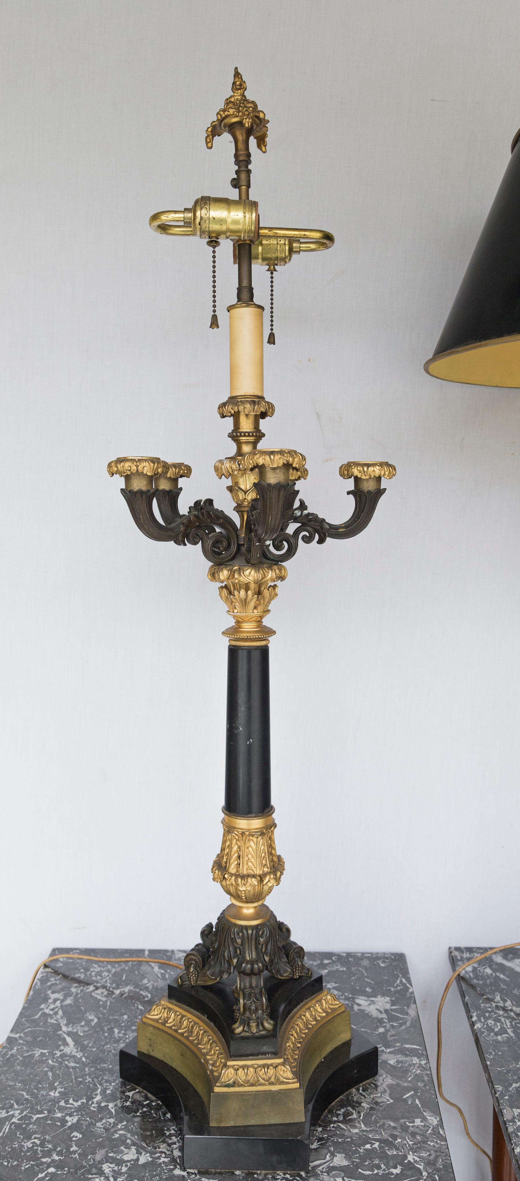 Five patinated arms with gilt bronze candle cups surround a central, taller electrified light of S shaped cluster bulb sockets above an off white 