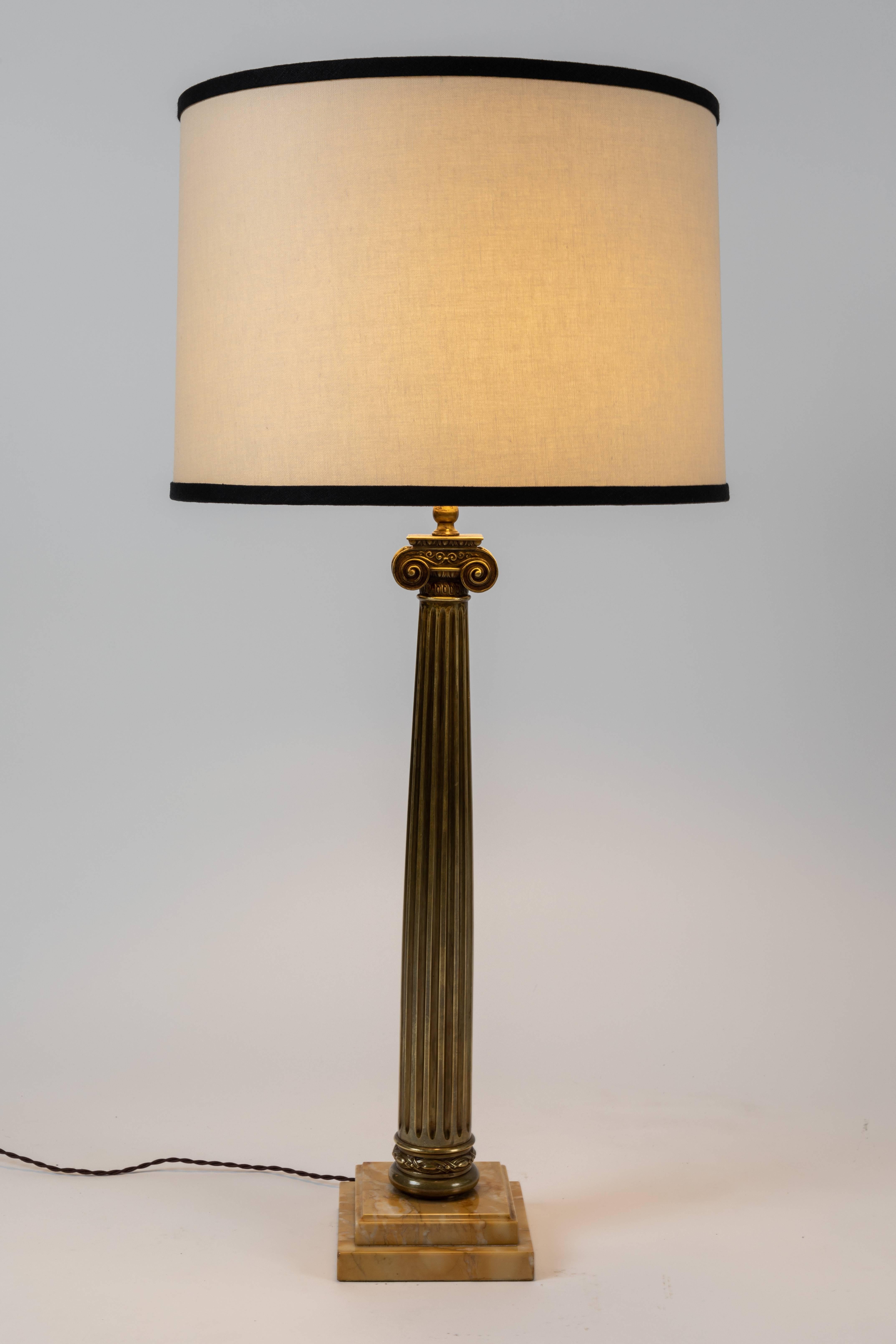 Handsome pair of patinated brass Roman column table lamps with marble bases. The shades are newly designed and custom made. Each lamp features a Ionic Order style column / capital. 

The Ionic capital is characterized by the use of volutes. The