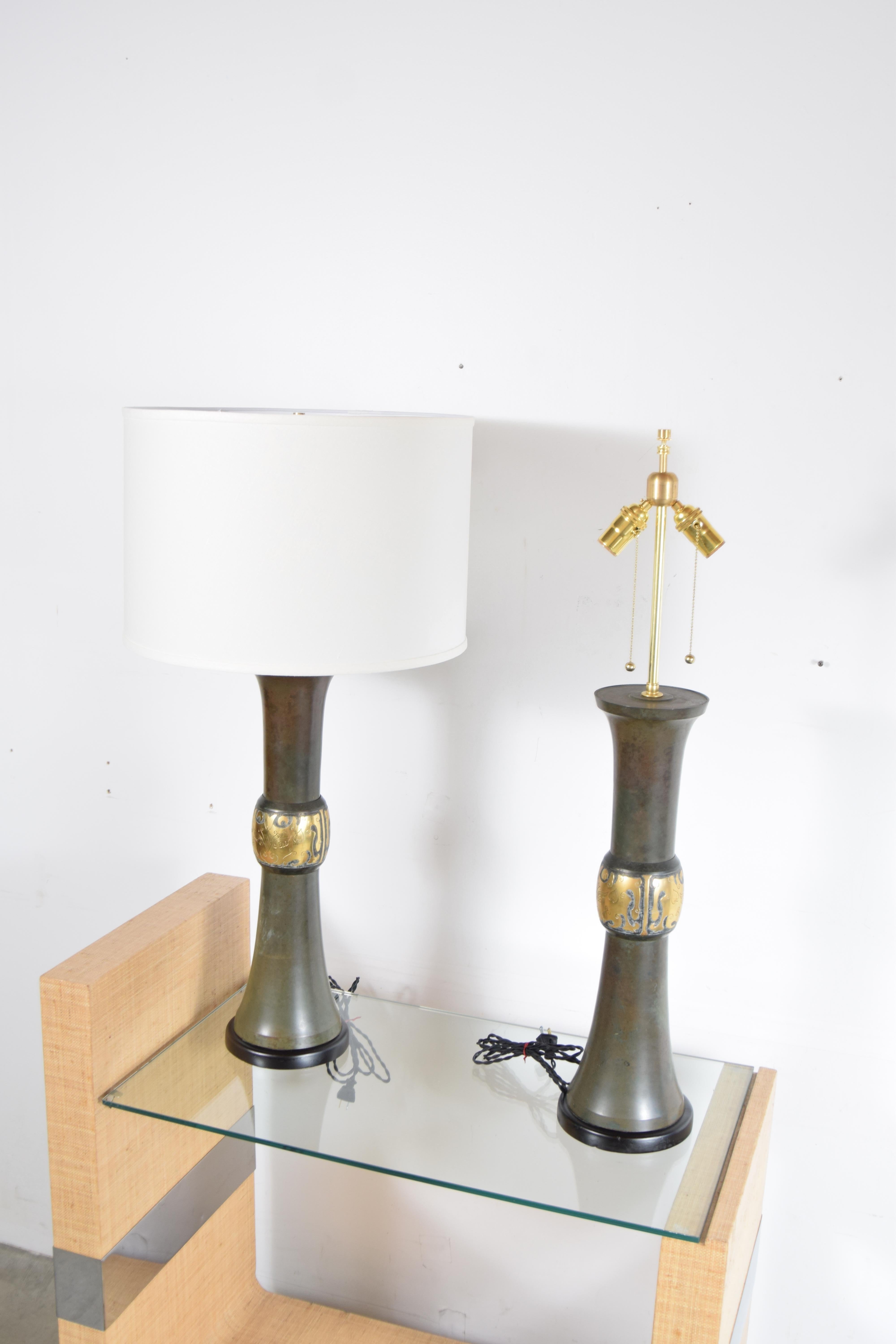 Pair of bronze and brass, Asian motif lamps, circa 1955. Lamps have been completely re-wired, and new top of the line brass hardware has been added, as has brand new shades. Lamps stand 35 1/2