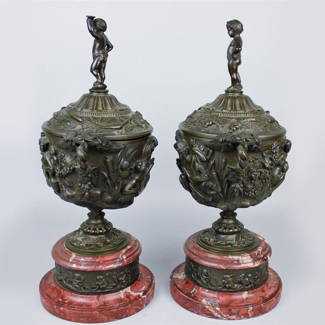 A fine pair of patinated bronze and rouge griotte marble urns and covers, in the manner of Clodion.

Of fine patina each urn has an ovoid shaped body cast in high relief with vine leaves and bacchanalian figures, with leaf cast handles and domed