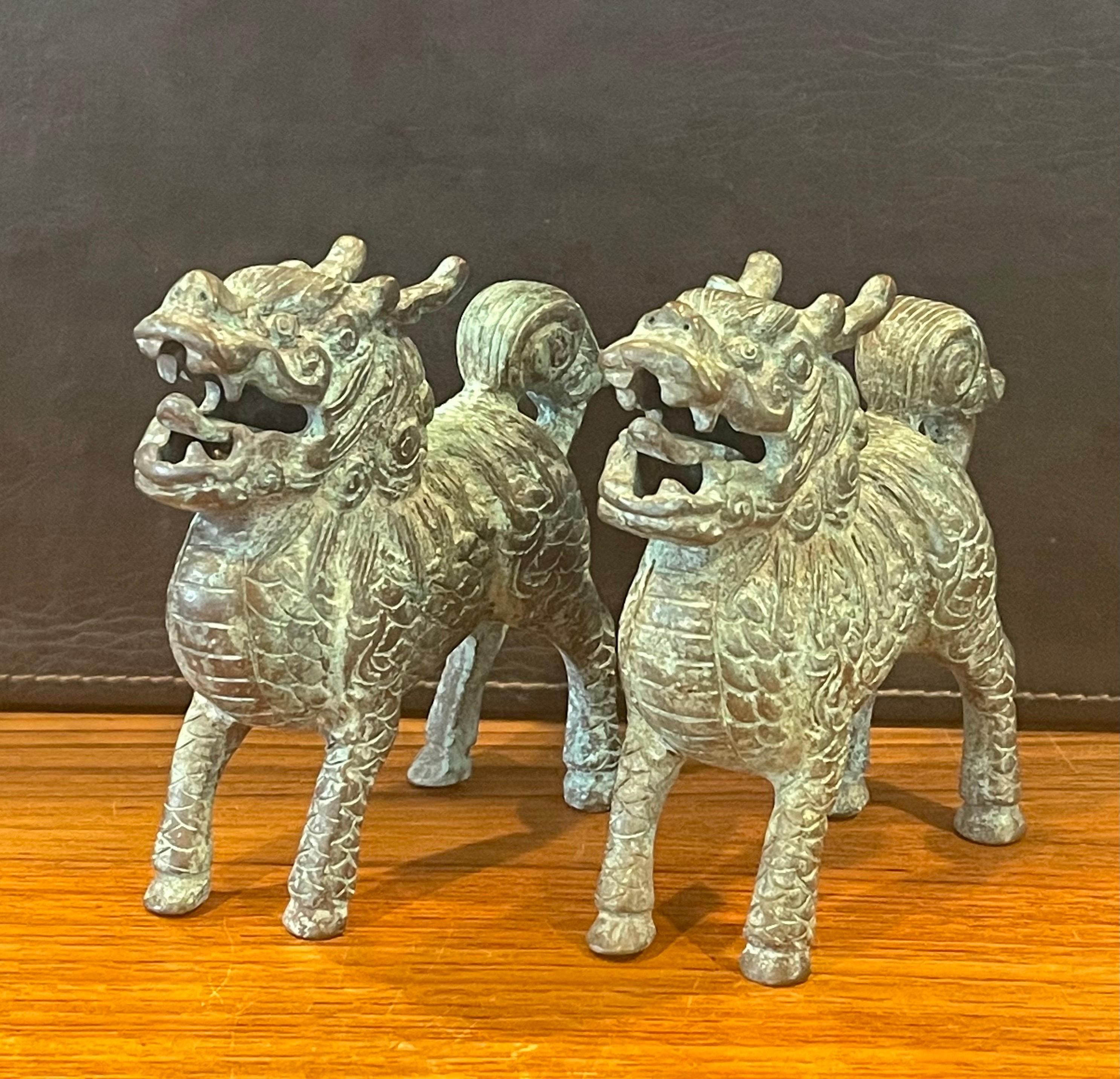 Pair of patinated bronze Chinese foo dogs with a verdigris finish, circa 1980s. The pair are in very good condition with amazing detail and a gorgeous patina. Each dog measures 5.75