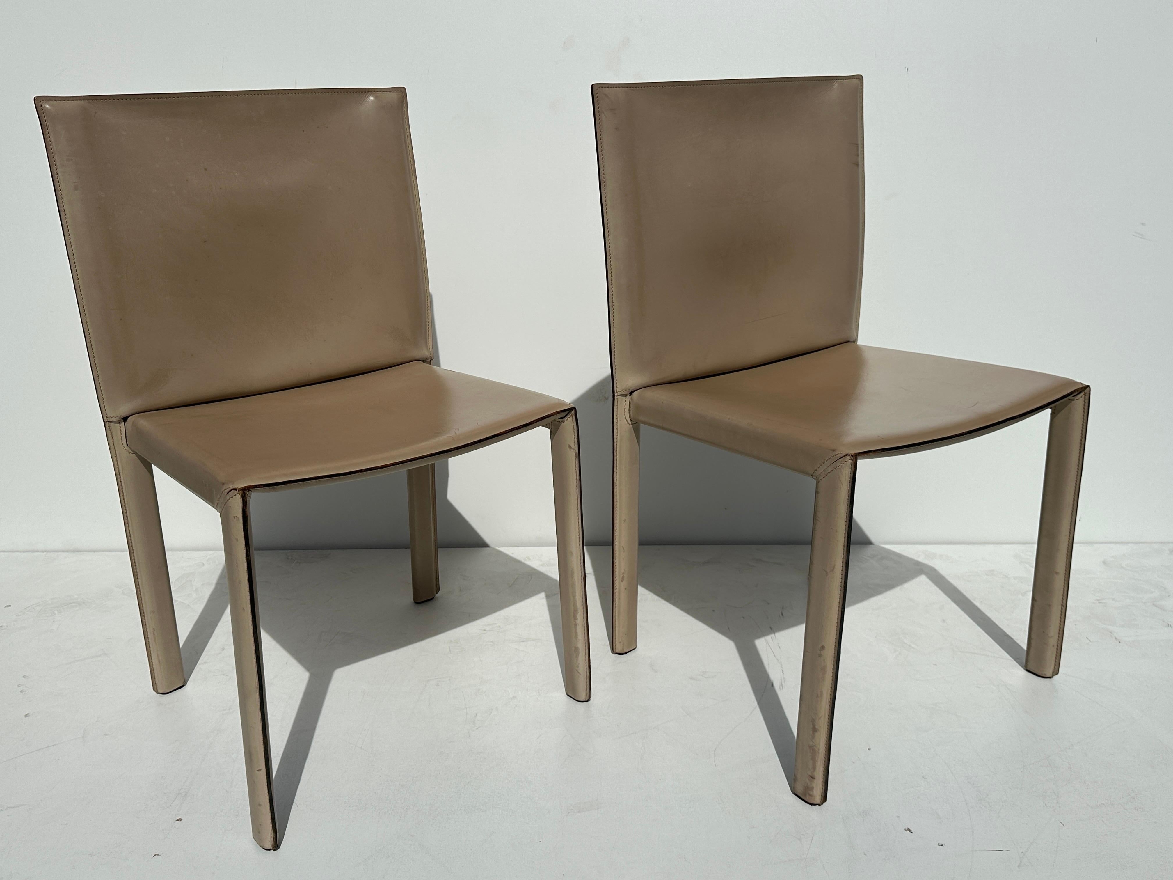 Pair of patinated saddle stitched leather side chairs by Enrico Pellizzoni.
All stitching are intact with no tears. Normal wear of use with beautiful natural patina.