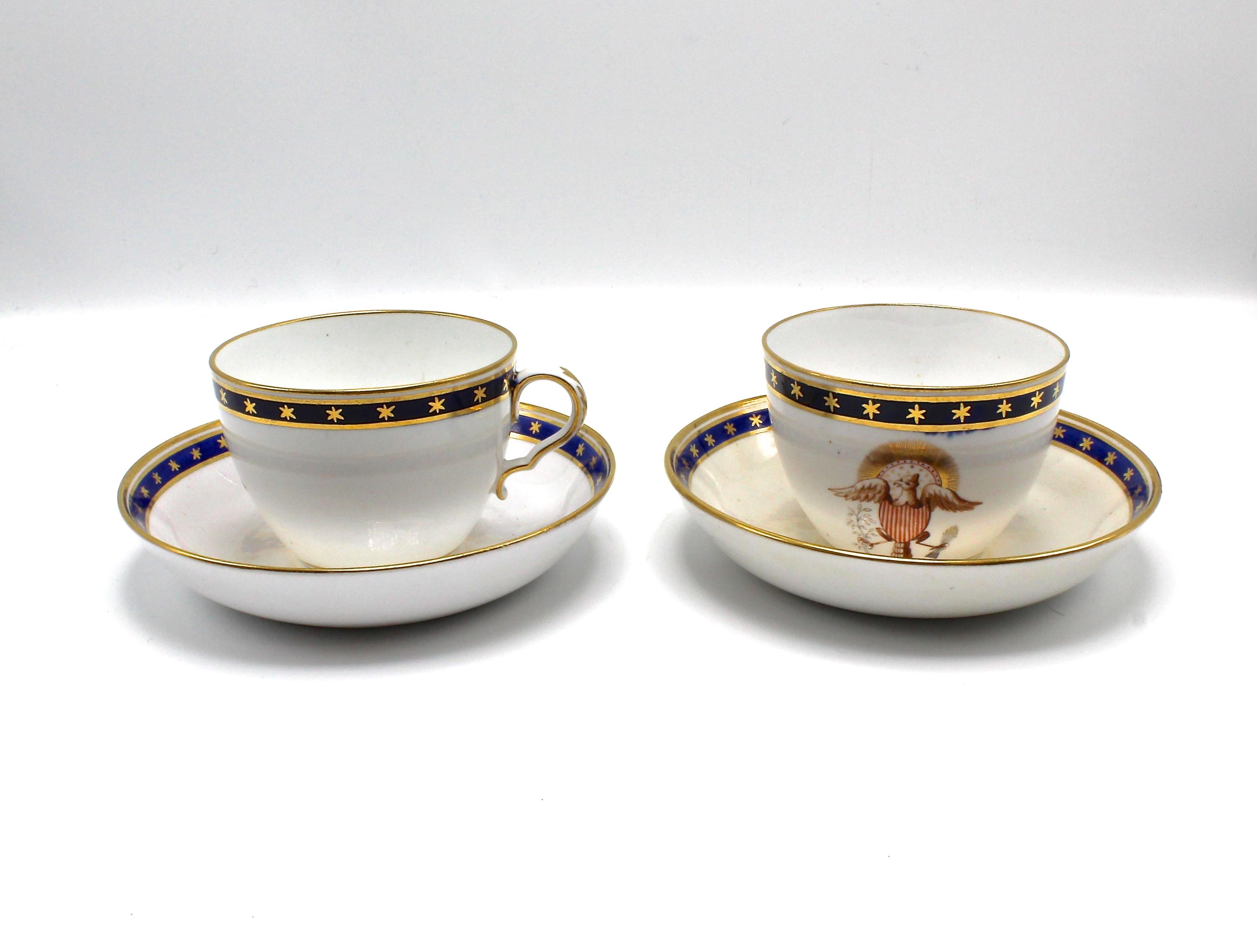 This is a beautifully matched pair of patriotic American eagle teacups and saucers from the 1840s. They are made of bone china with a thick cobalt blue top border design with gold stars, gold outer pinstripes, and a gold top rim edge. They feature a