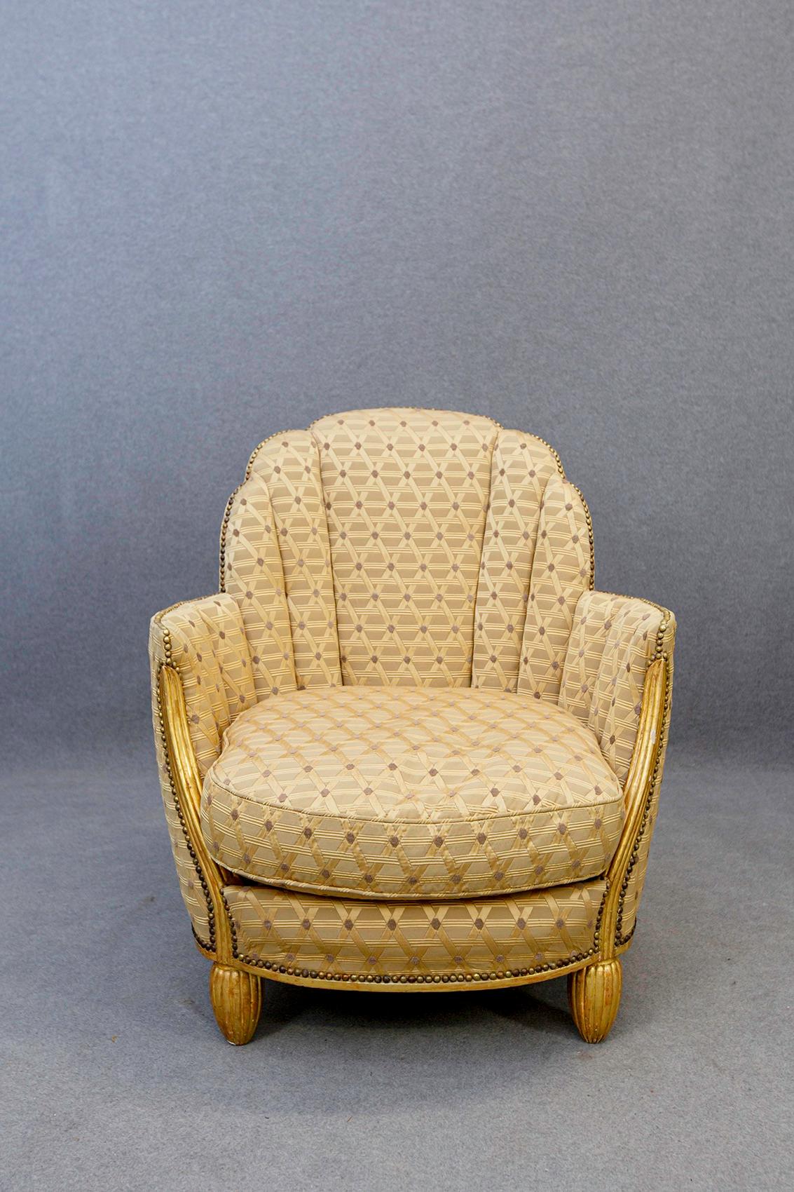 Pair of Paul Follot armchairs from the 1920s and 1930s. The chairs have a wide, curved backrest that extends over solid armrests and rests on legs. The armchairs are made of carved gilded wood. Upholstered in a rich draped fabric with golden yellow