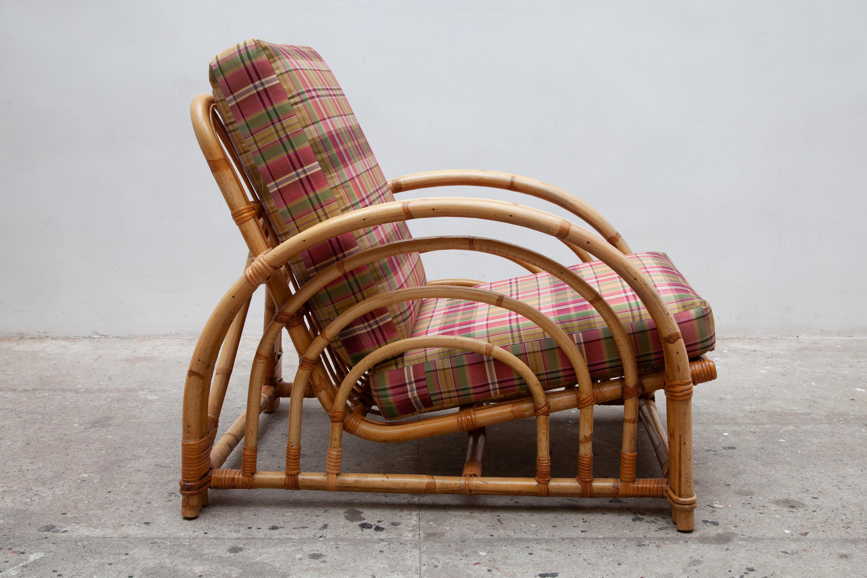 One of bend bamboo lounge chairs in the style of Paul Frankl. Features sculptural circular armrests and colorful plaid cushions. This Art Deco-inspired set retains a timeless style that would look great in any modern space. This lightweight yet