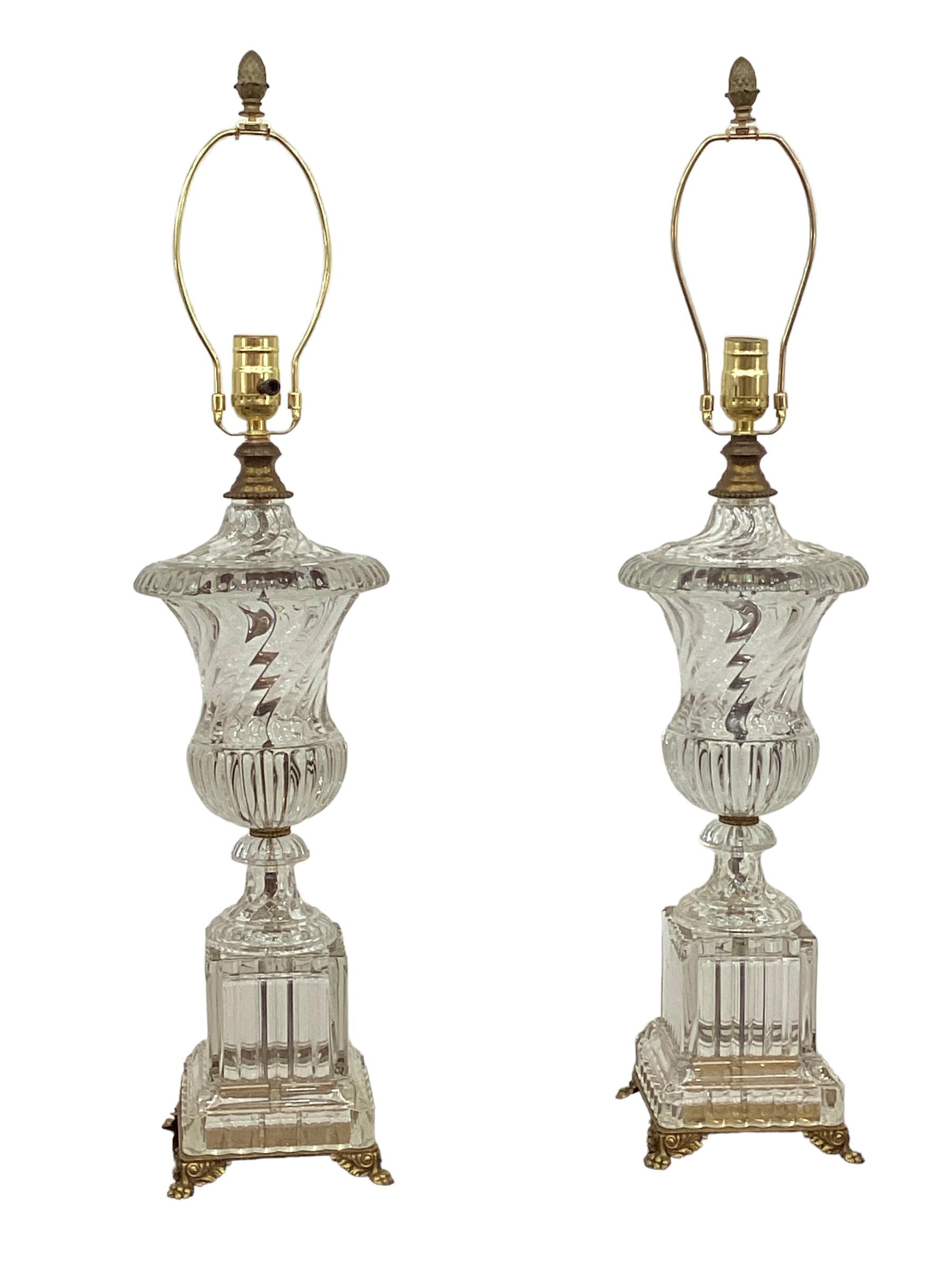Pair of Paul Hanson Swirled Urn Glass Lamps from original Baccarat molds. Heavy leaded glass urns in the classic Baccarat swirled design sits atop a square plinth. The lamps are mounted on square brass bases with paw feet. Wired and in working
