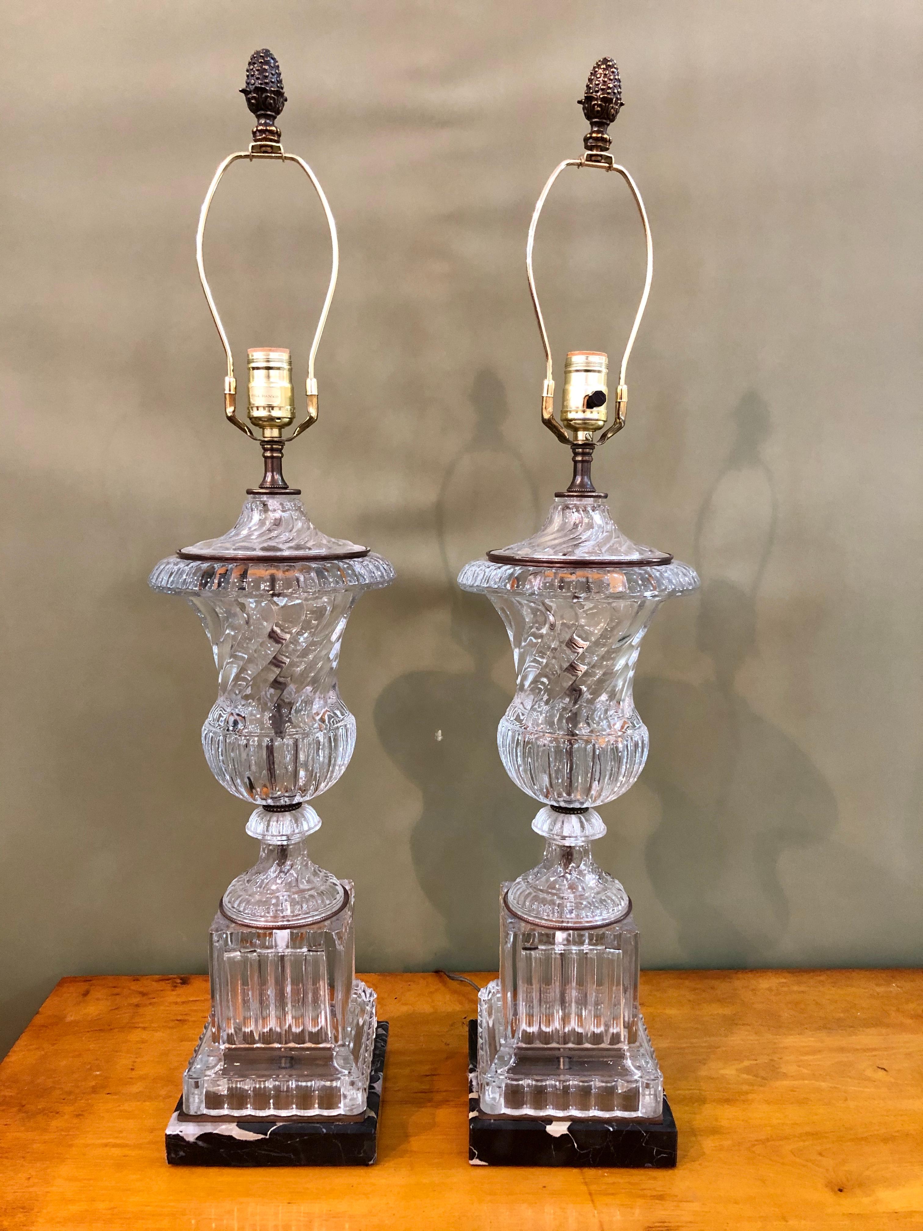 Pair of Paul Hanson Urn Lamps from original Baccarat molds. Heavy leaded urn in the classic Baccarat swirled design with a square plinth sits atop a black square marble base. Wired and in working condition. 